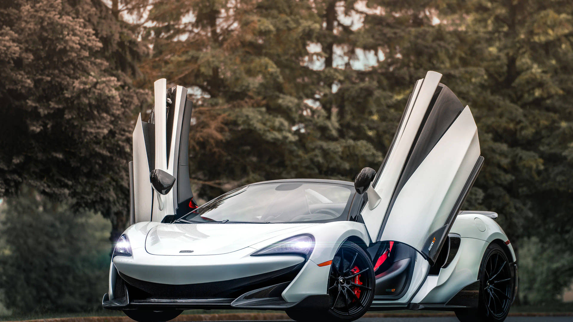 銀色McLaren跑車在樹林地區打開鷗翼車門。
