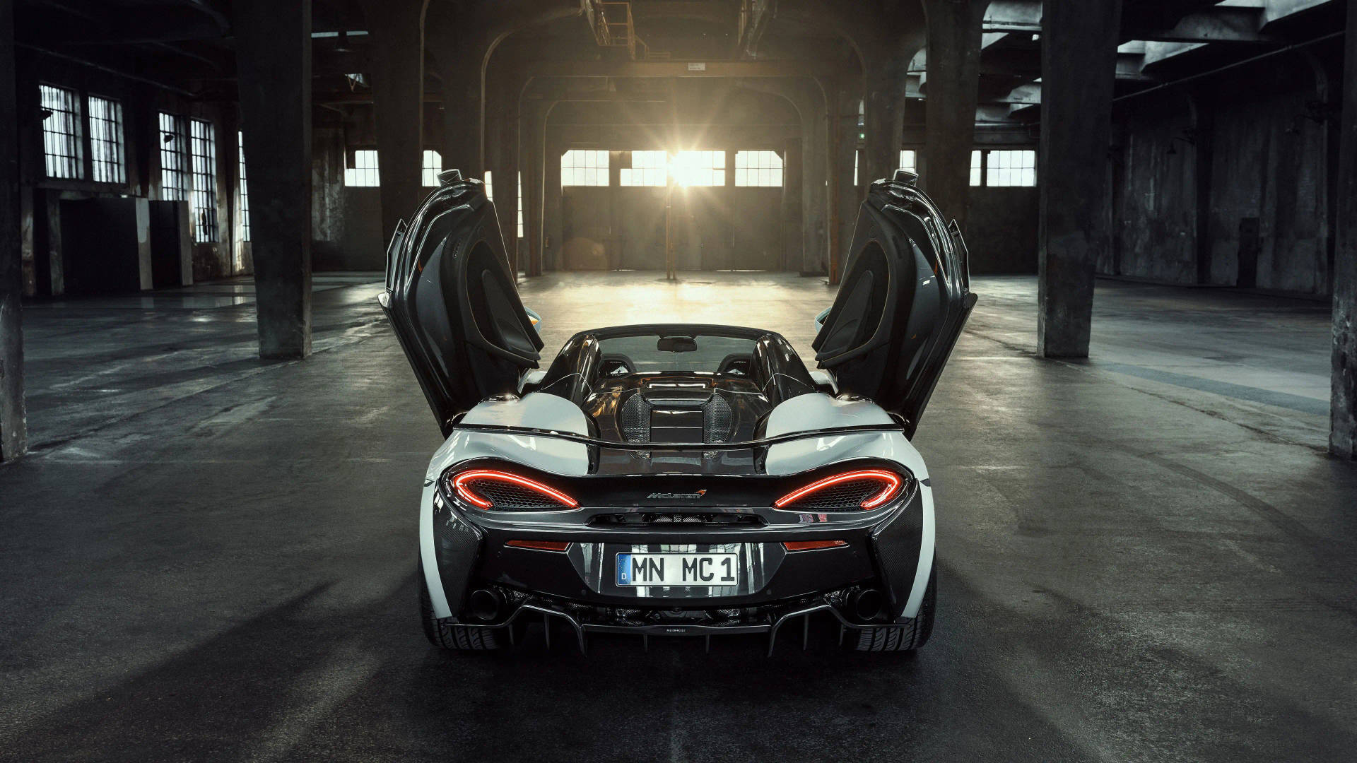 白色McLaren跑車打開車門，停在陽光普照的工業倉庫中。