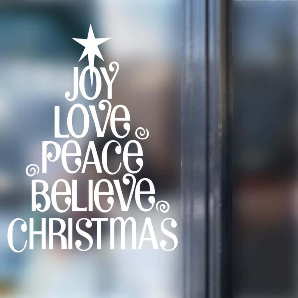 白色聖誕樹形文字貼紙貼在玻璃門上，寫著 joy love peace believe christmas。