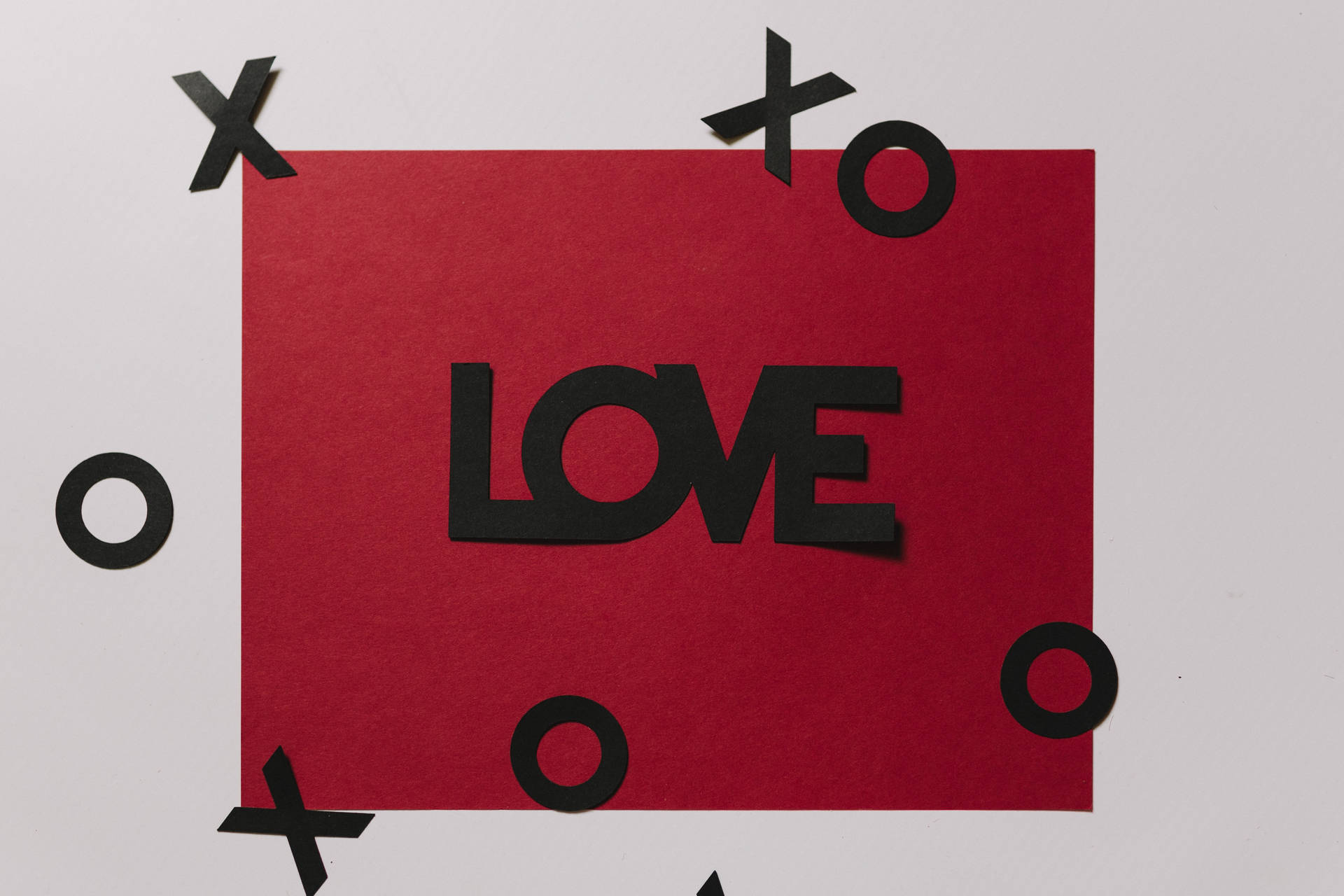 紅色紙張上有黑色字母 LOVE，周圍有 X 和 O 剪紙。