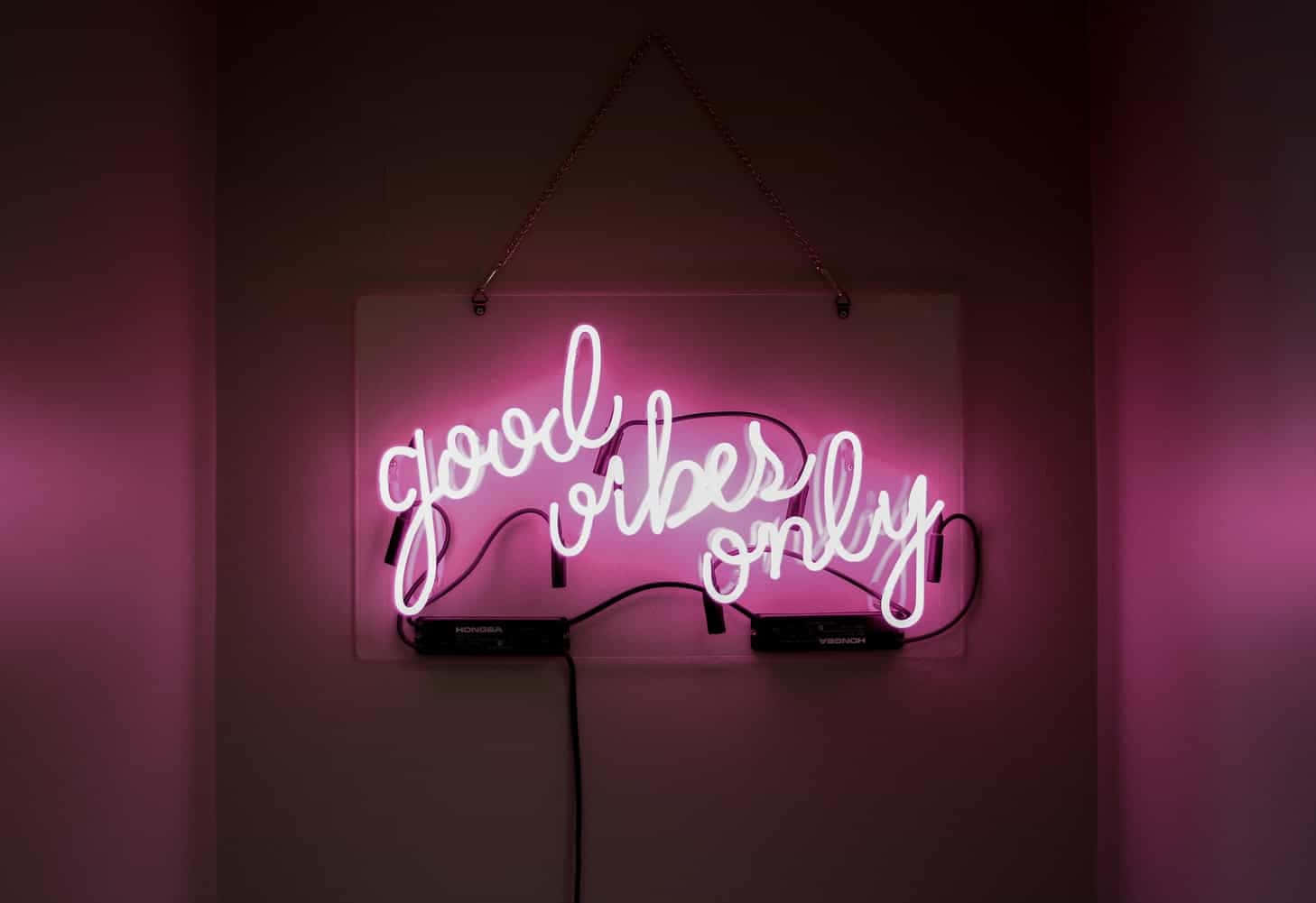 粉紅色霓虹燈牌，上面寫著 good vibes only，掛在黑暗的牆上。