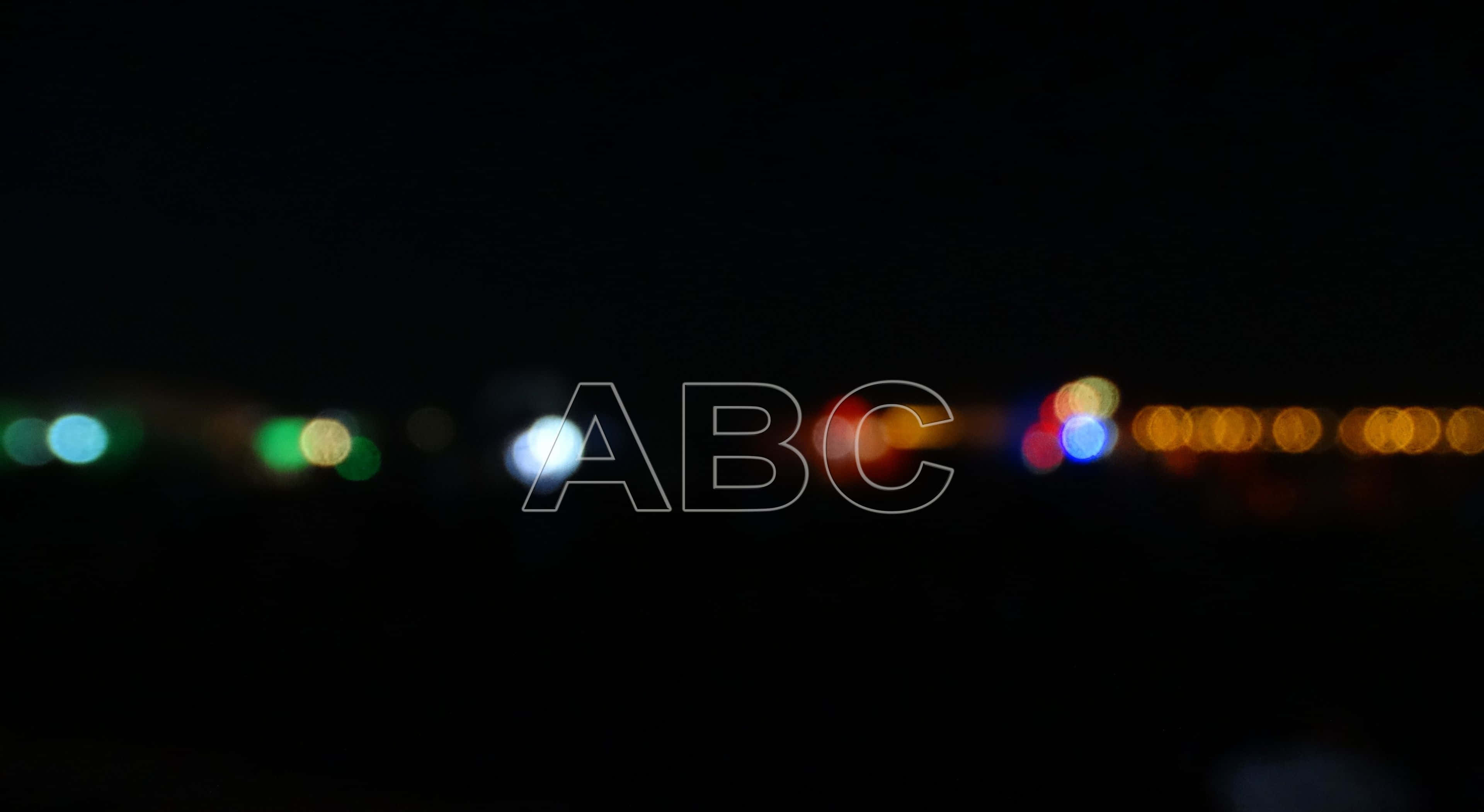 Abc 桌布 壁紙 — 散景燈光在漆黑的夜空中柔和發光，帶有微弱的ABC水印疊加。