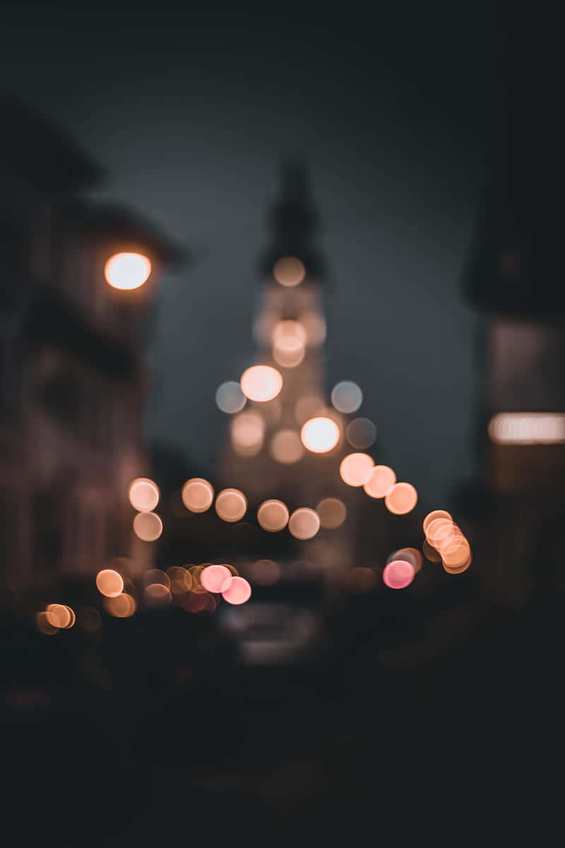 黑色電話 桌布 壁紙 — 散景燈光在黑暗的城市夜空下溫暖地發光，遠處有模糊的教堂尖塔。