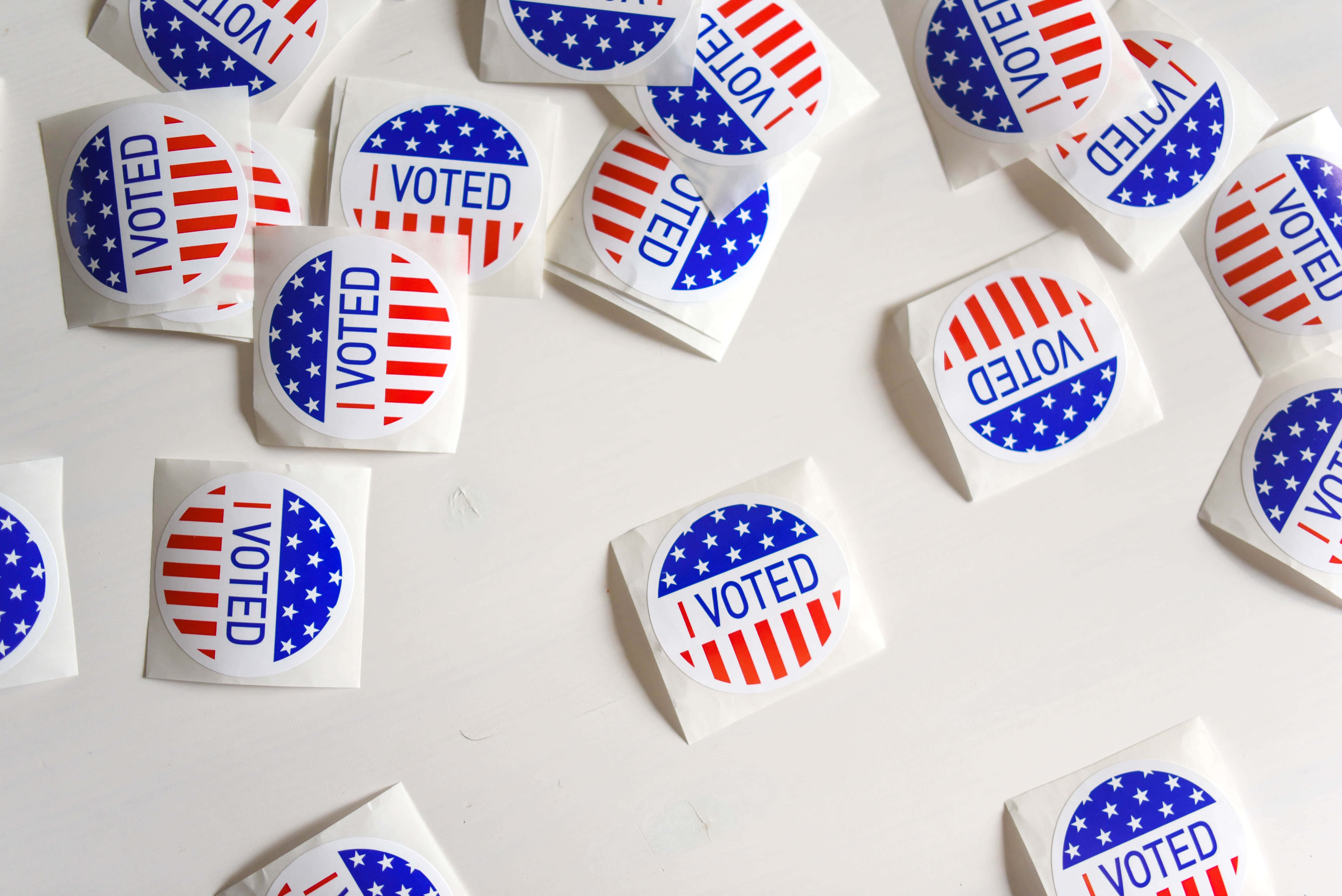 Election 桌布 壁紙 — 散落嘅「我投咗票」貼紙，有美國國旗設計，喺純白表面上。