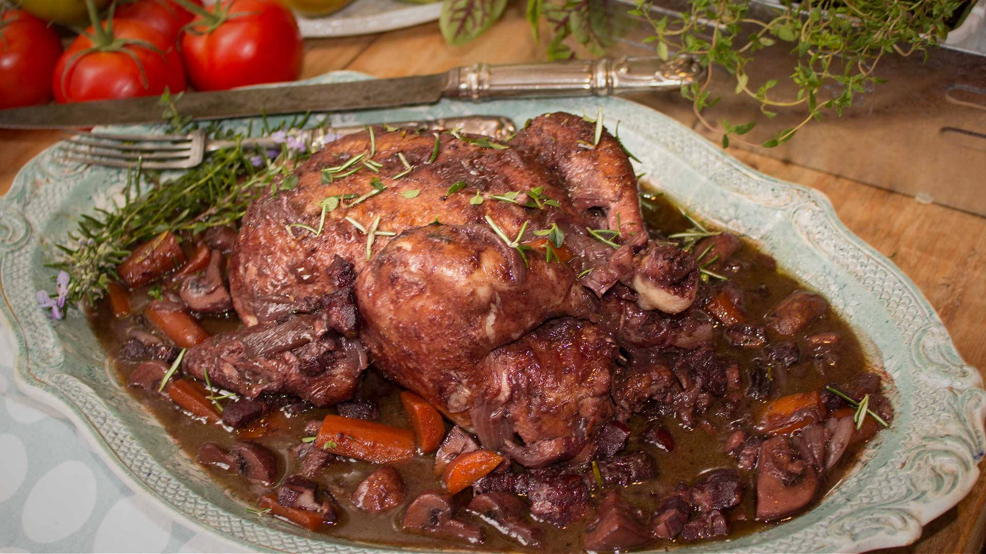 整隻燉煮雞肉的Coq Au Vin 壁紙 — 烤雞配上濃郁的棕色醬汁，搭配胡蘿蔔、蘑菇和新鮮香草，盛放在華麗的盤子上。