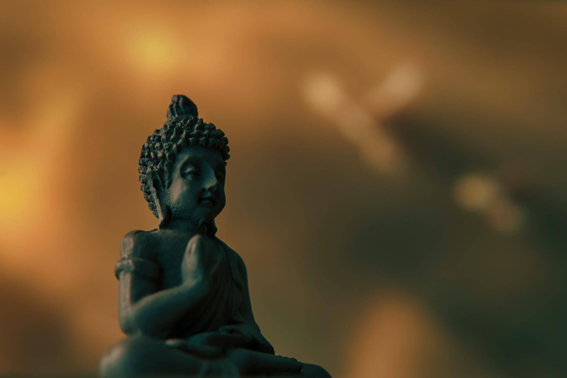 整體佛像壁紙 壁紙 — 一尊寧靜的佛像在溫暖的金色散景背景下打坐冥想。