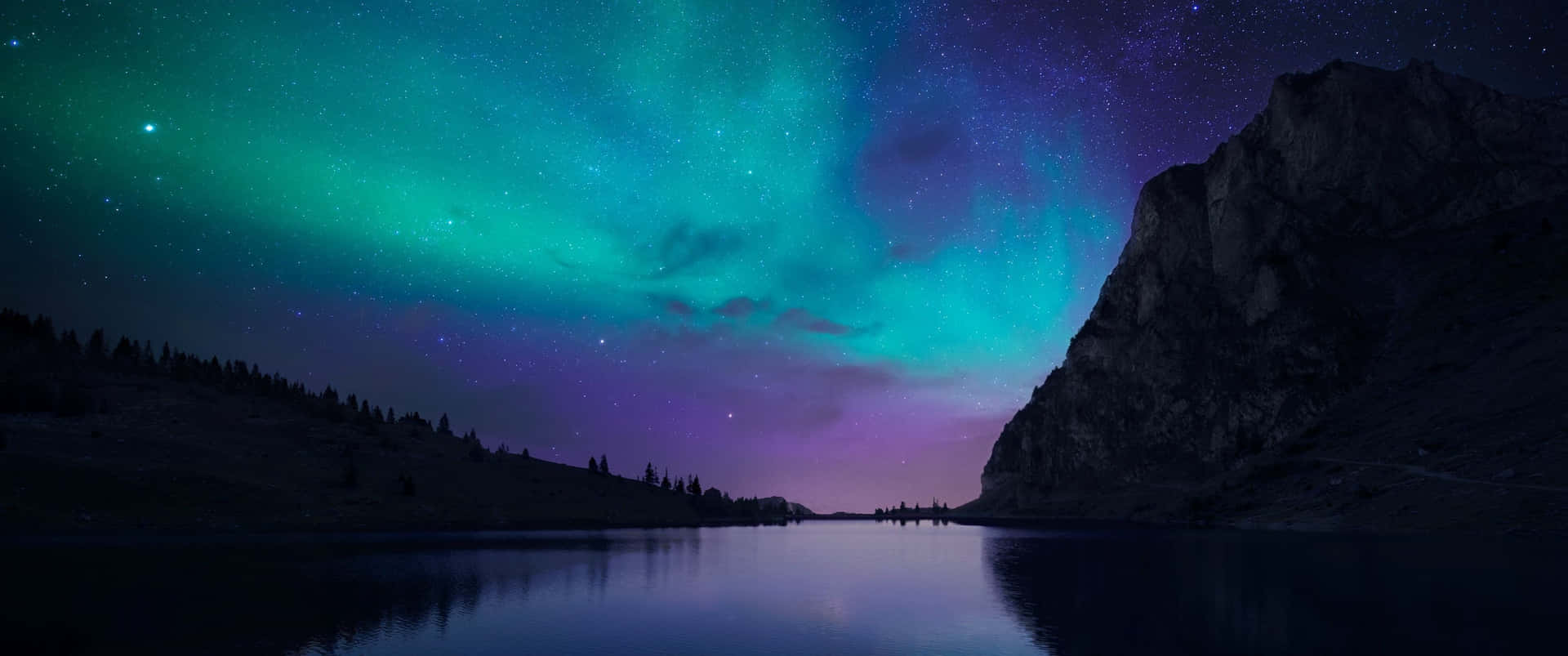 北極光在星空下照耀著湖泊和山脈。