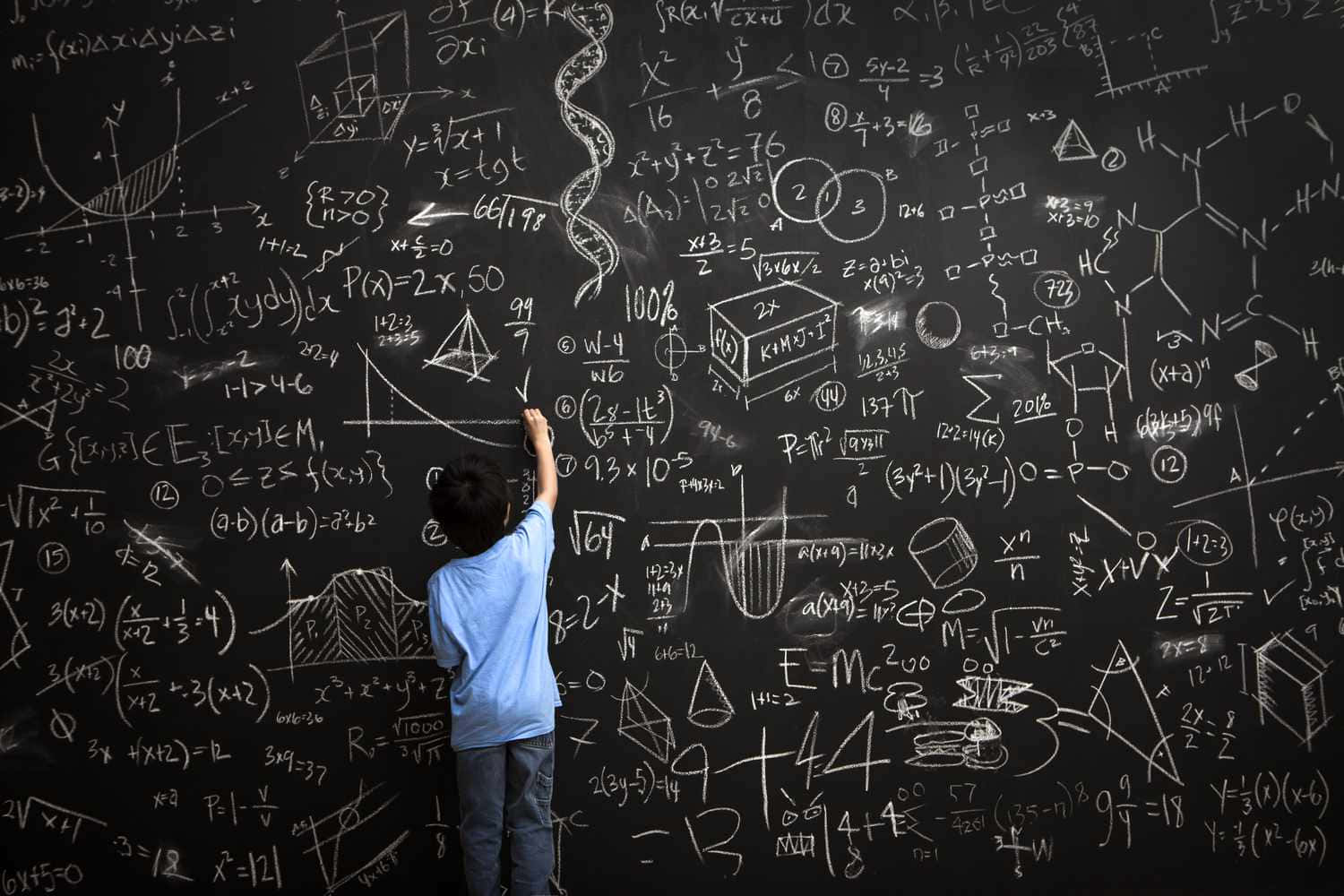 孩子在充滿科學公式的黑板上解數學方程式。