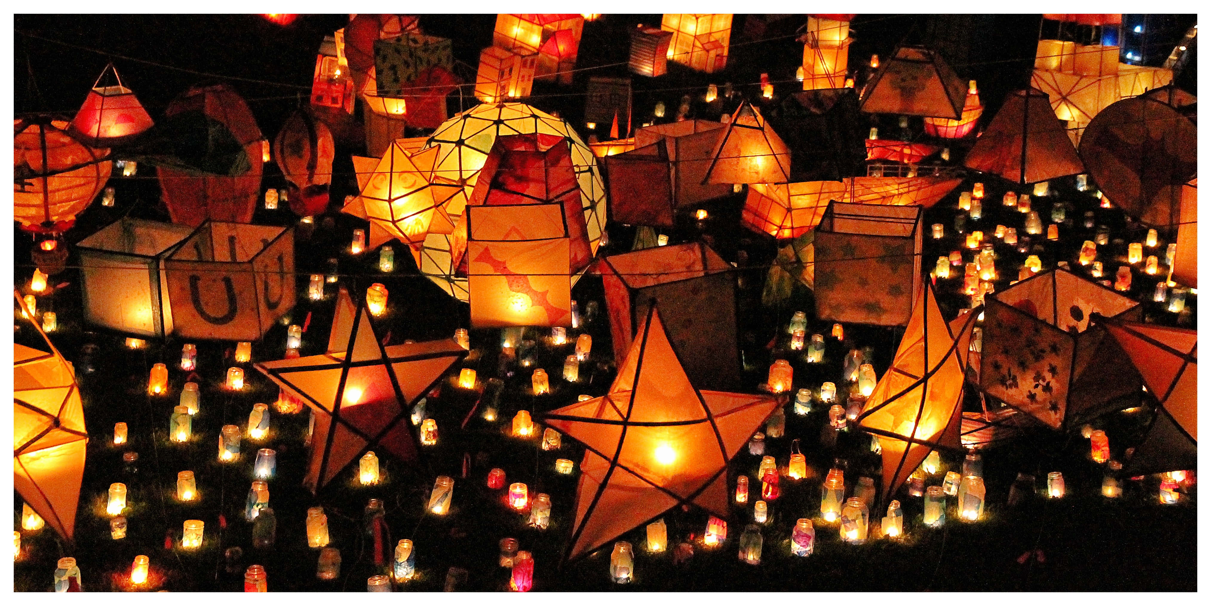 Fall Festival 桌布 壁紙 — 數百盞發光的紙燈籠和蠟燭在黑暗的夜空中漂浮和懸掛，營造出溫暖神奇的氛圍。