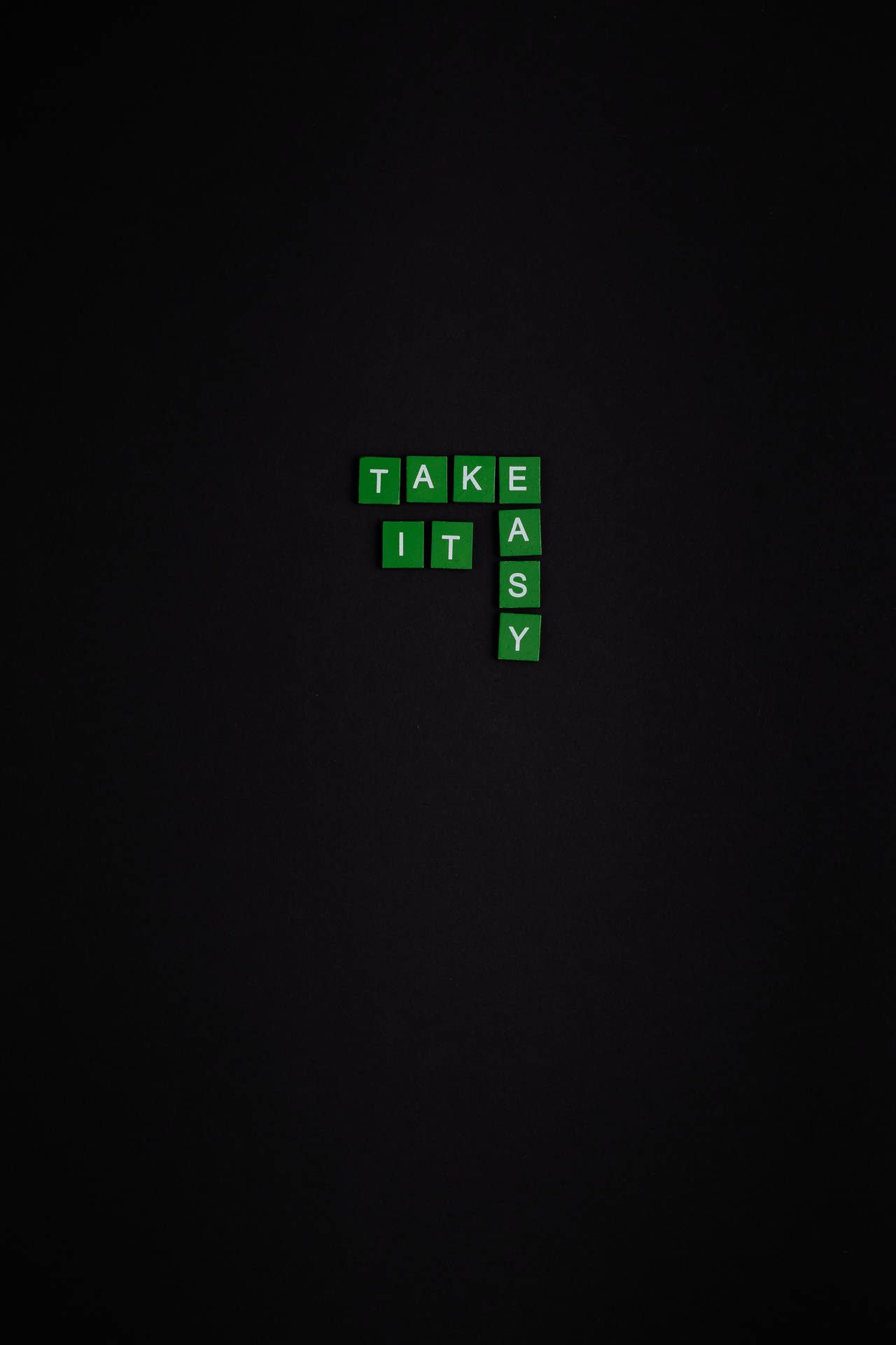 深色背景上拼出 'TAKE IT AS Y' 的綠色 Scrabble 風格瓷磚。