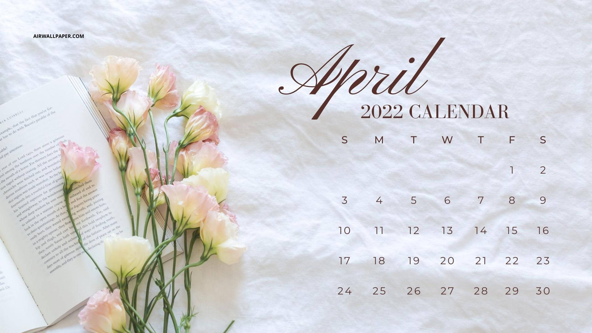2022年4月日曆，粉紅色花朵和打開的書本在白色布料上。