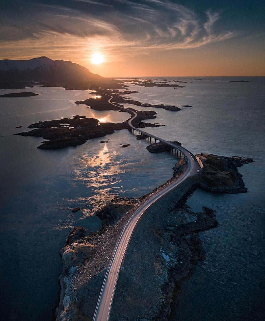 日落時分一條蜿蜒的海岸公路，水面上有金色的倒影。