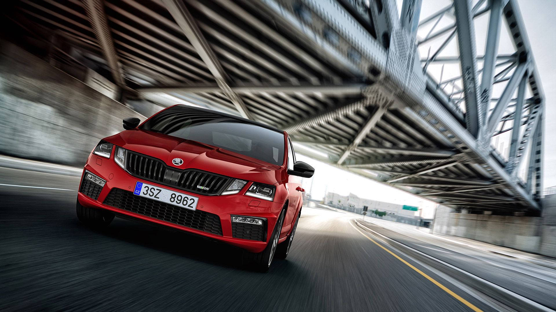 紅色Skoda Octavia RS在高速公路上的鋼橋下疾馳。