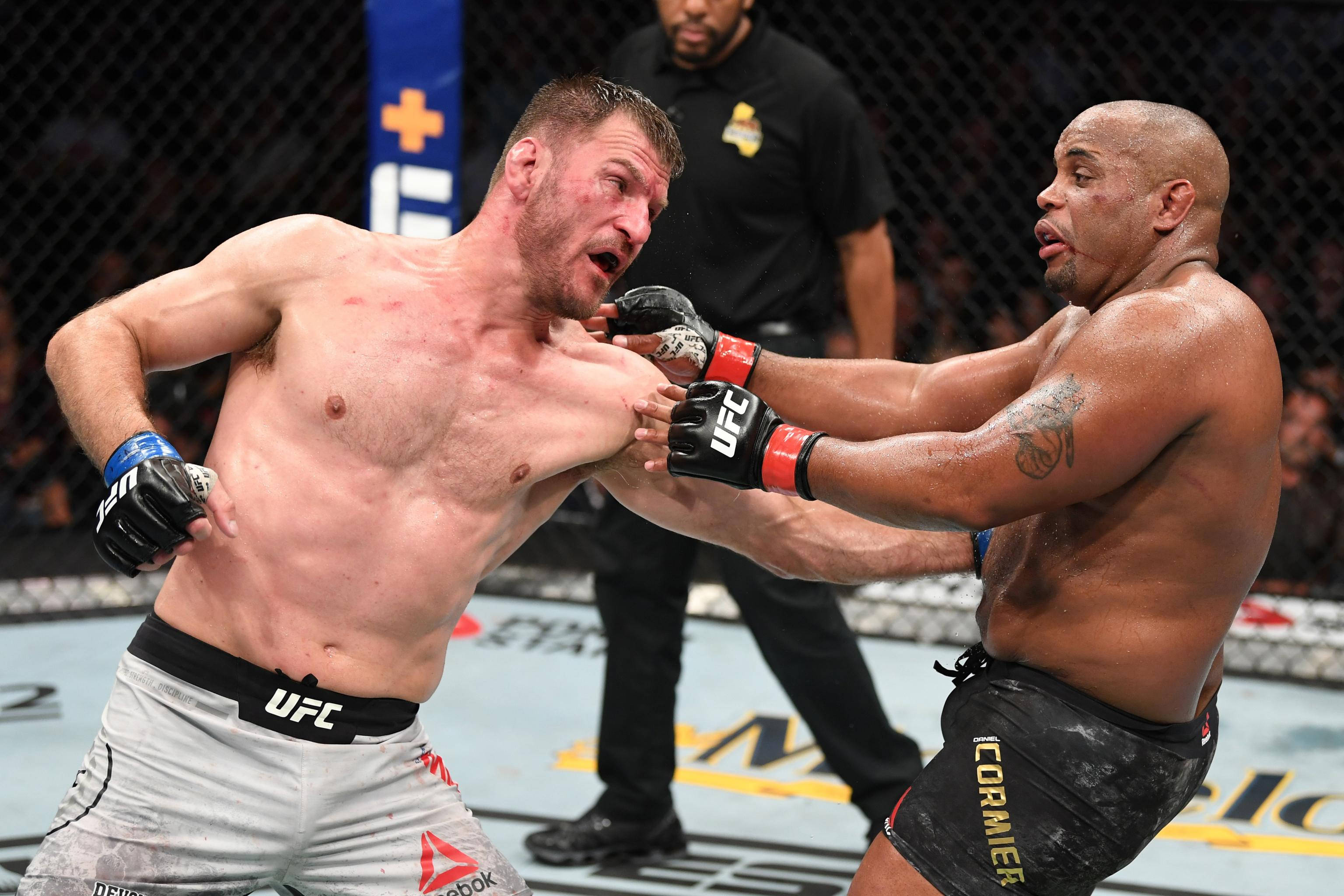 斯泰普·米奧西克強力左勾拳 壁紙 — 兩名拳手在一場殘酷的 UFC 比賽中交鋒，汗水飛濺，裁判密切注視。