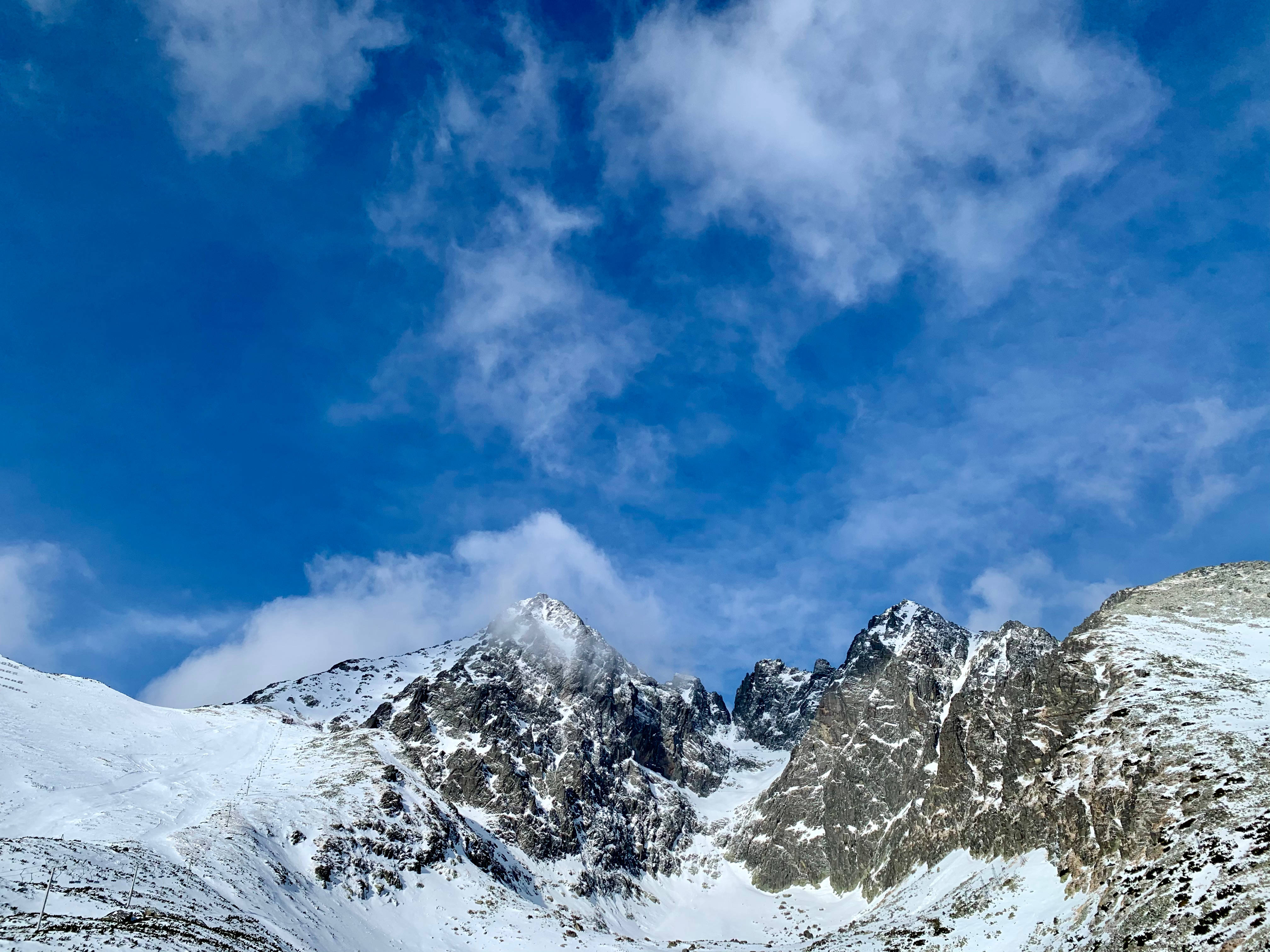 斯洛伐克山峰俯瞰 壁紙 — 白雪覆蓋的山峰刺穿了一片充滿活力的藍天，天空中有縷縷白雲。