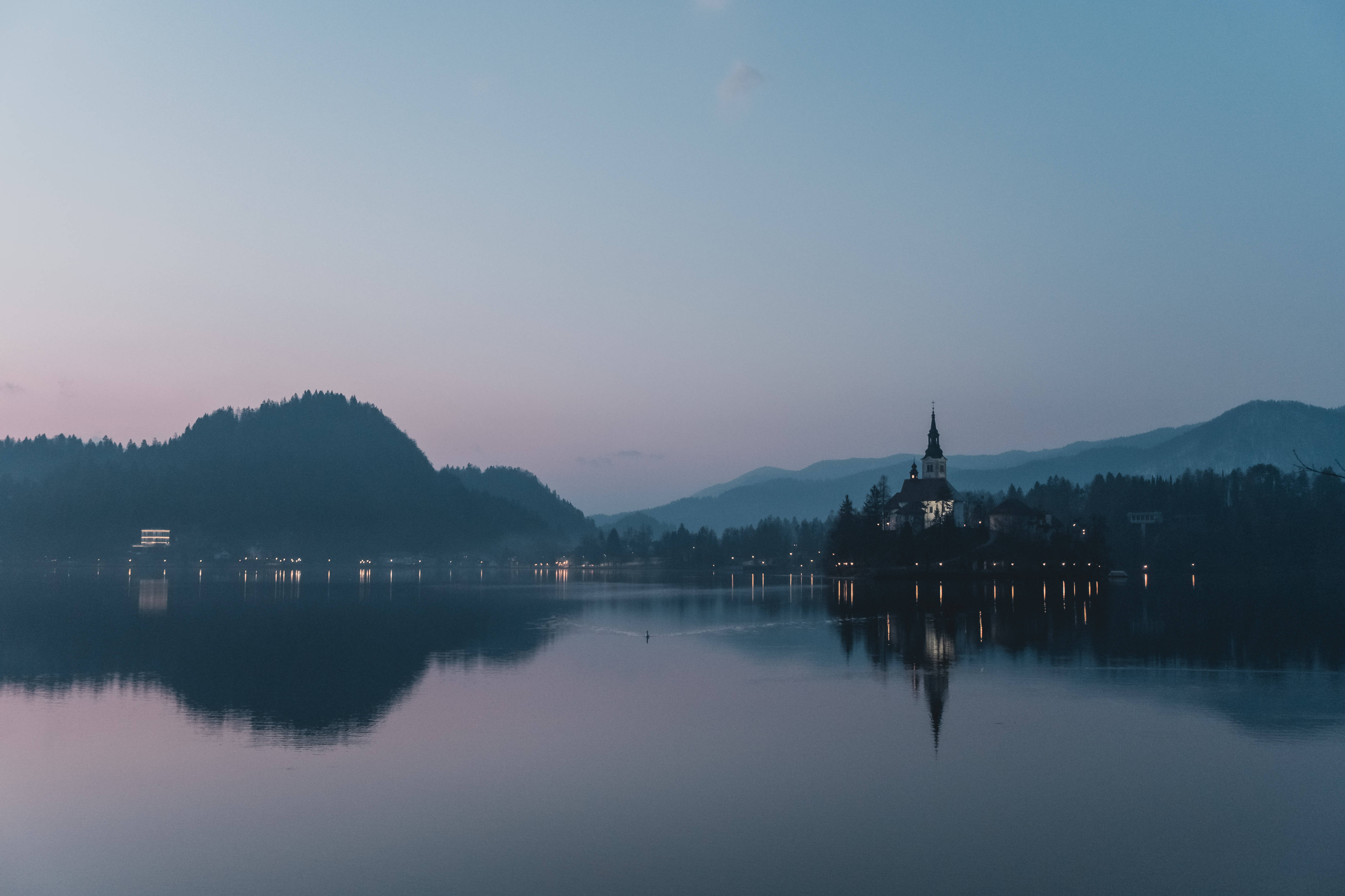 斯洛維尼亞布萊德湖全景 壁紙 — 寧靜的暮色湖泊在柔和的紫色和藍色天空下倒映著教堂和遠山。
