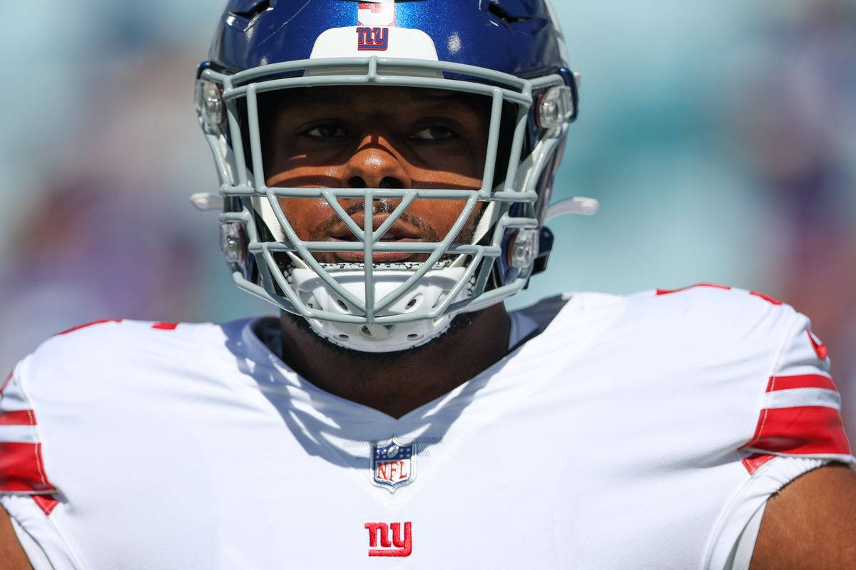 NFL美式足球員身穿白色球衣和藍色頭盔在球場上