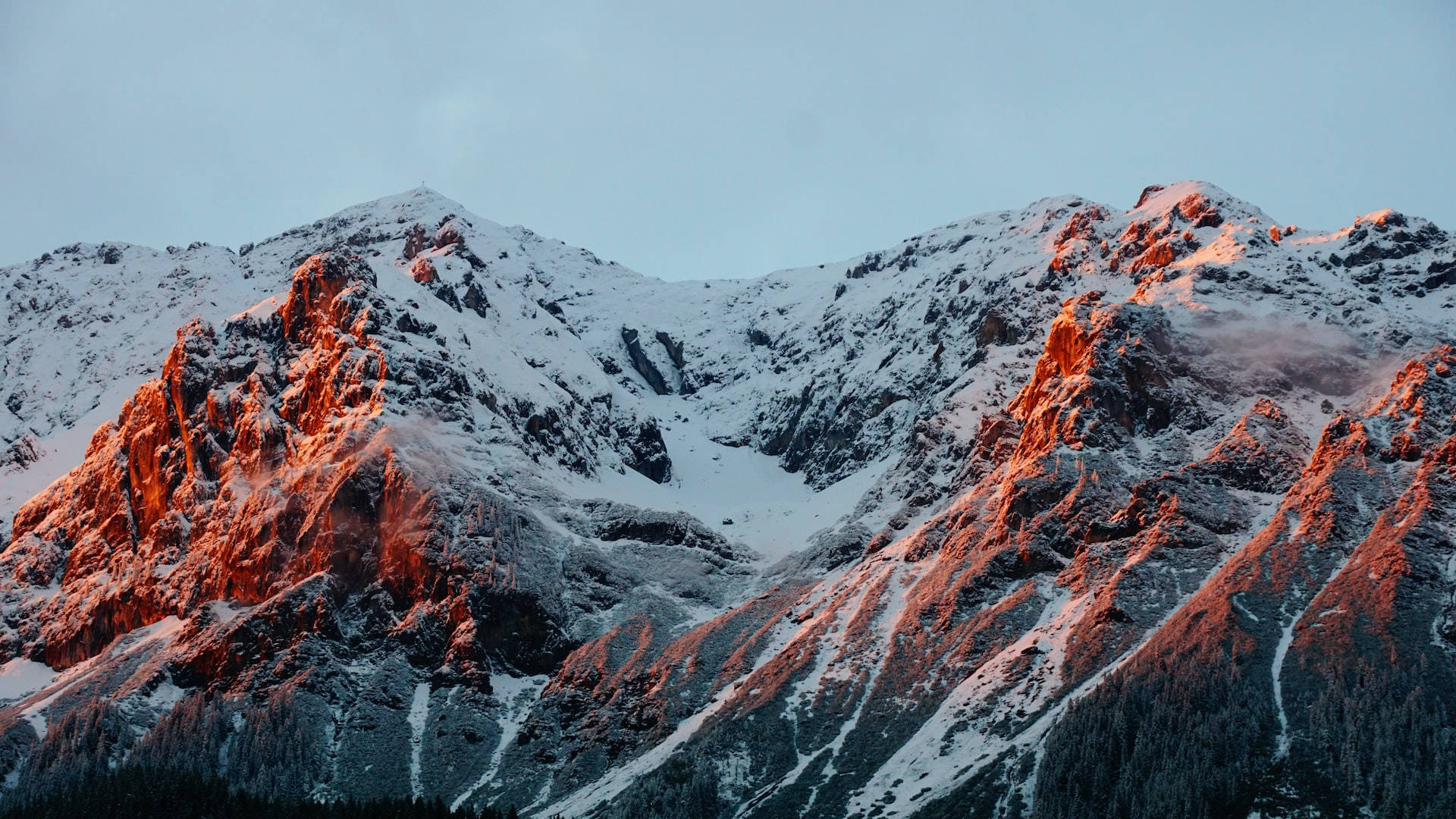 積雪的山峰沐浴在金色的夕陽光中，下方有深邃的陰影。