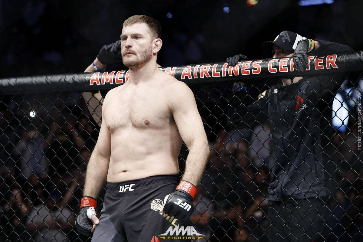 斯蒂普·米奧奇克賽前站立 壁紙 — 一位肌肉發達的MMA拳手站在美國航空中心的八角籠內，表情專注。