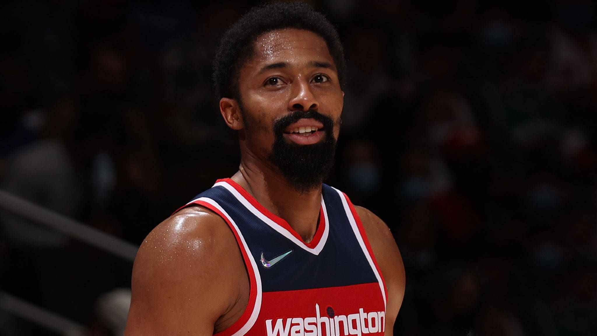 斯賓塞·丁威迪NBA球員 壁紙 — 一位身穿華盛頓球衣的專注籃球運動員在場館燈光下比賽時微微一笑。