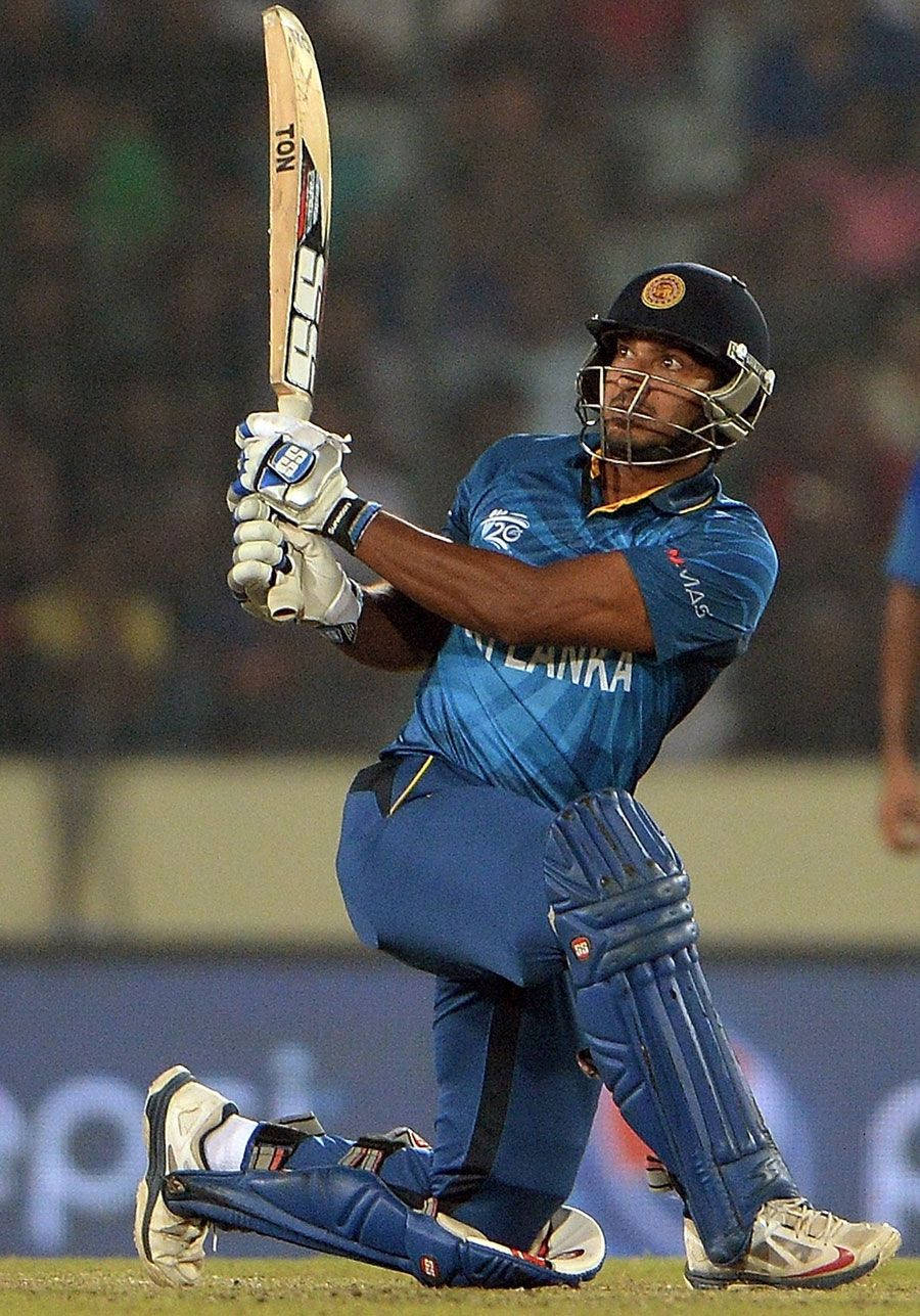 斯里蘭卡板球運動員Kumar Sangakkara 壁紙 — 一名身穿藍色球衣的斯里蘭卡板球擊球手在夜間比賽中，在球場燈光下強力揮動球棒。
