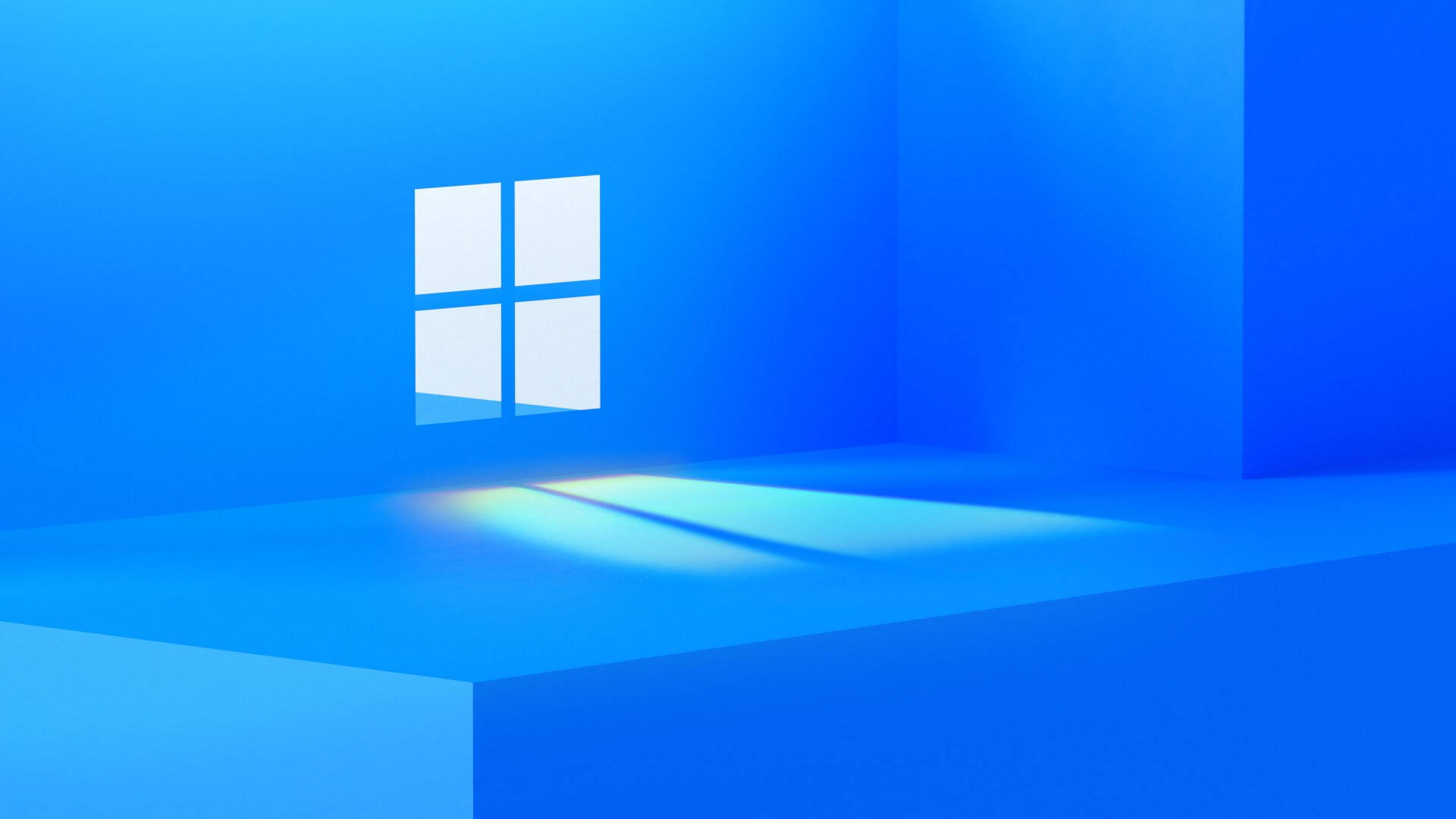 新Windows 11標誌 壁紙 — 一個極簡風格的藍色房間，帶有發光的Windows標誌，在地板上投射出柔和的光線。