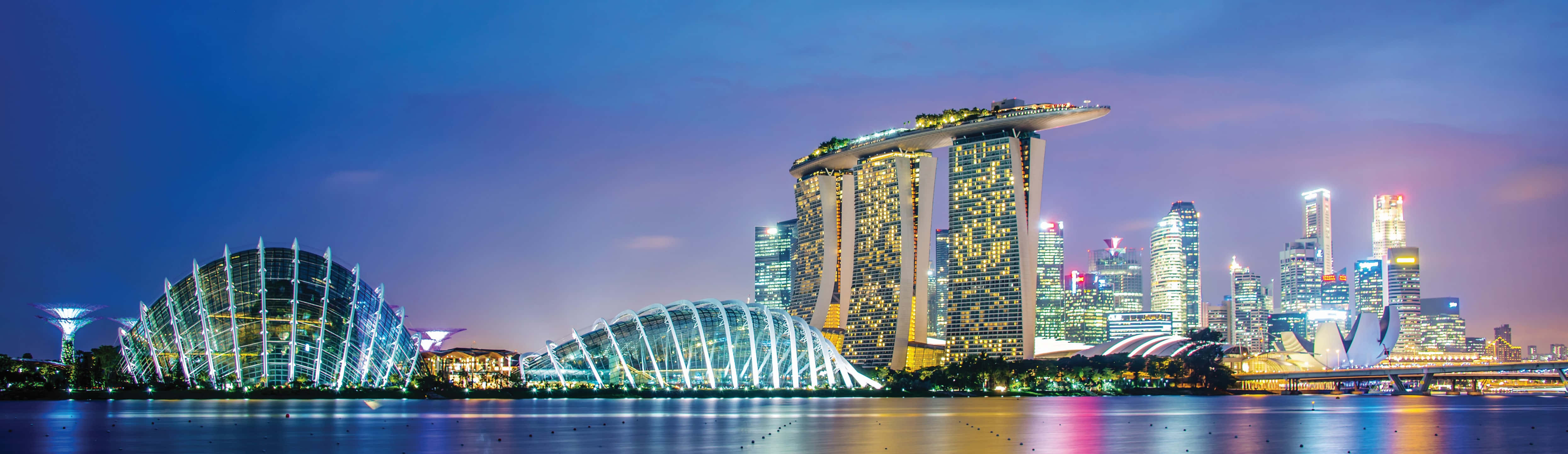 Singapore 桌布 壁紙 — 新加坡天際線在黃昏時分，濱海灣金沙和濱海灣花園在紫色天空下閃耀，倒映在平靜的水面上。
