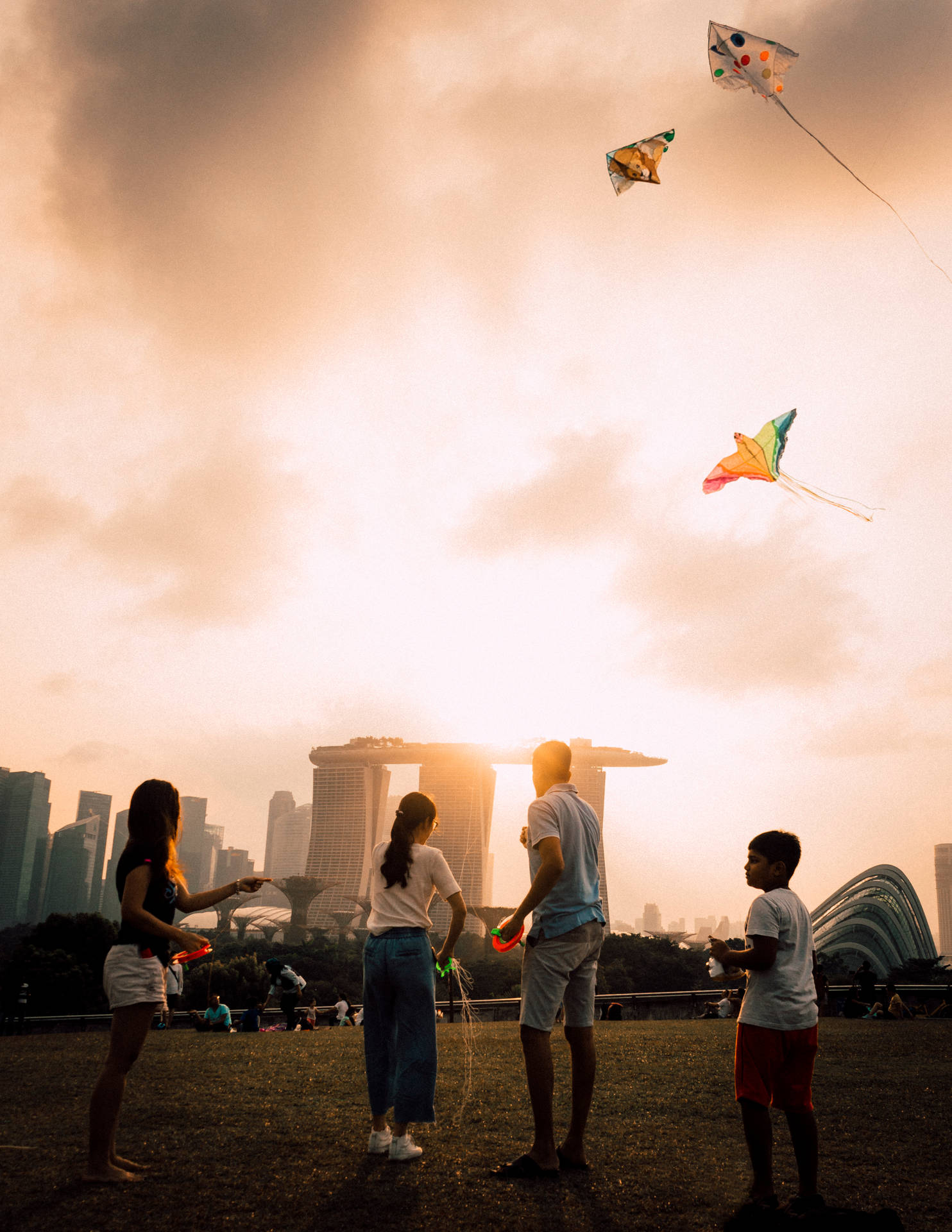 家人在日落時分在濱海灣金沙天際線附近放風箏。