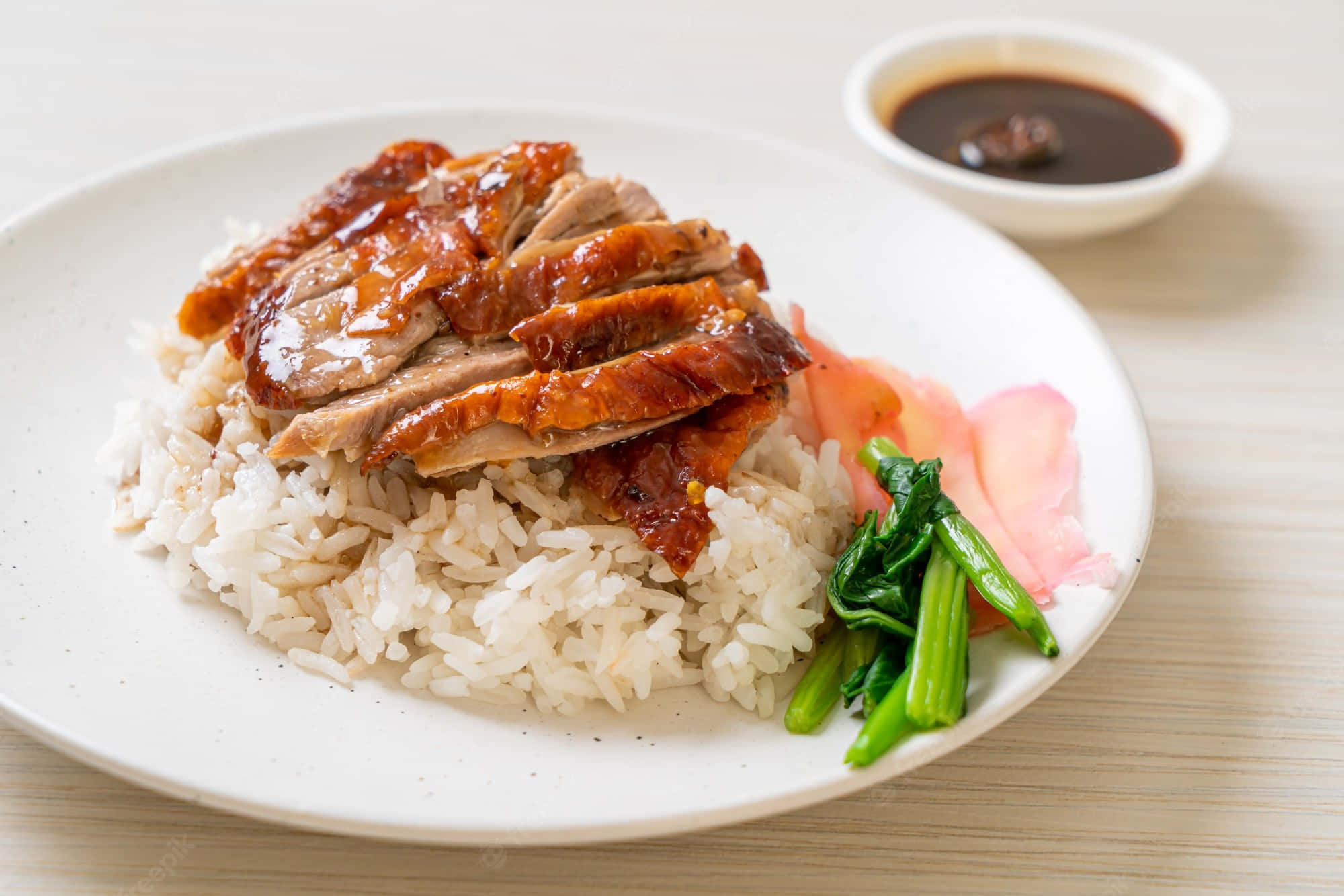 新加坡燒鴨飯，香氣撲鼻 壁紙 — 脆皮烤鴨片在白飯上閃閃發光，配上蒸青菜和醃蘿蔔，放在白色盤子上。