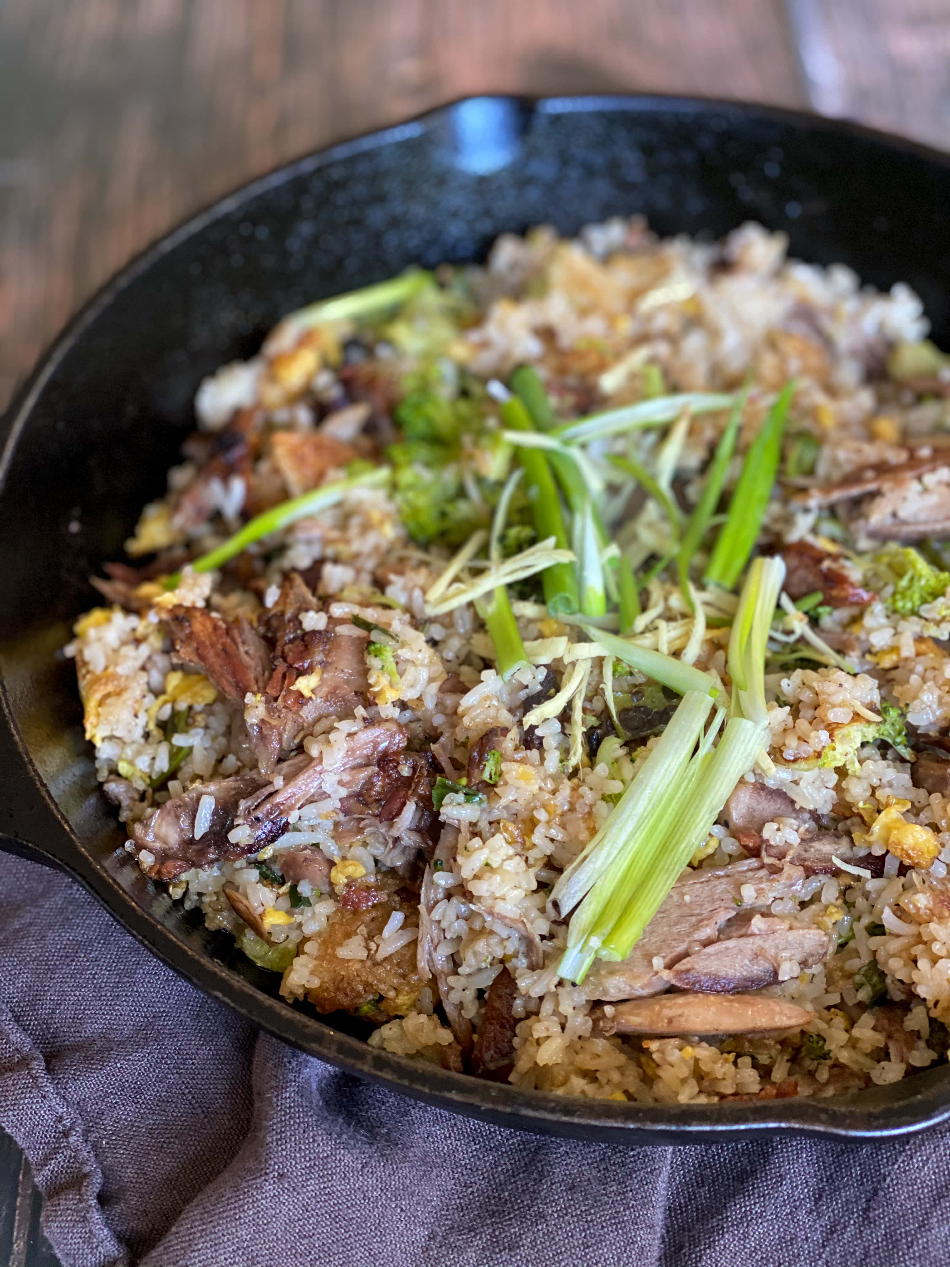新加坡美味：無麩質炸鴨飯 壁紙 — 鑄鐵煎鍋裝滿美味的炒飯，上面放有青蔥和脆肉。