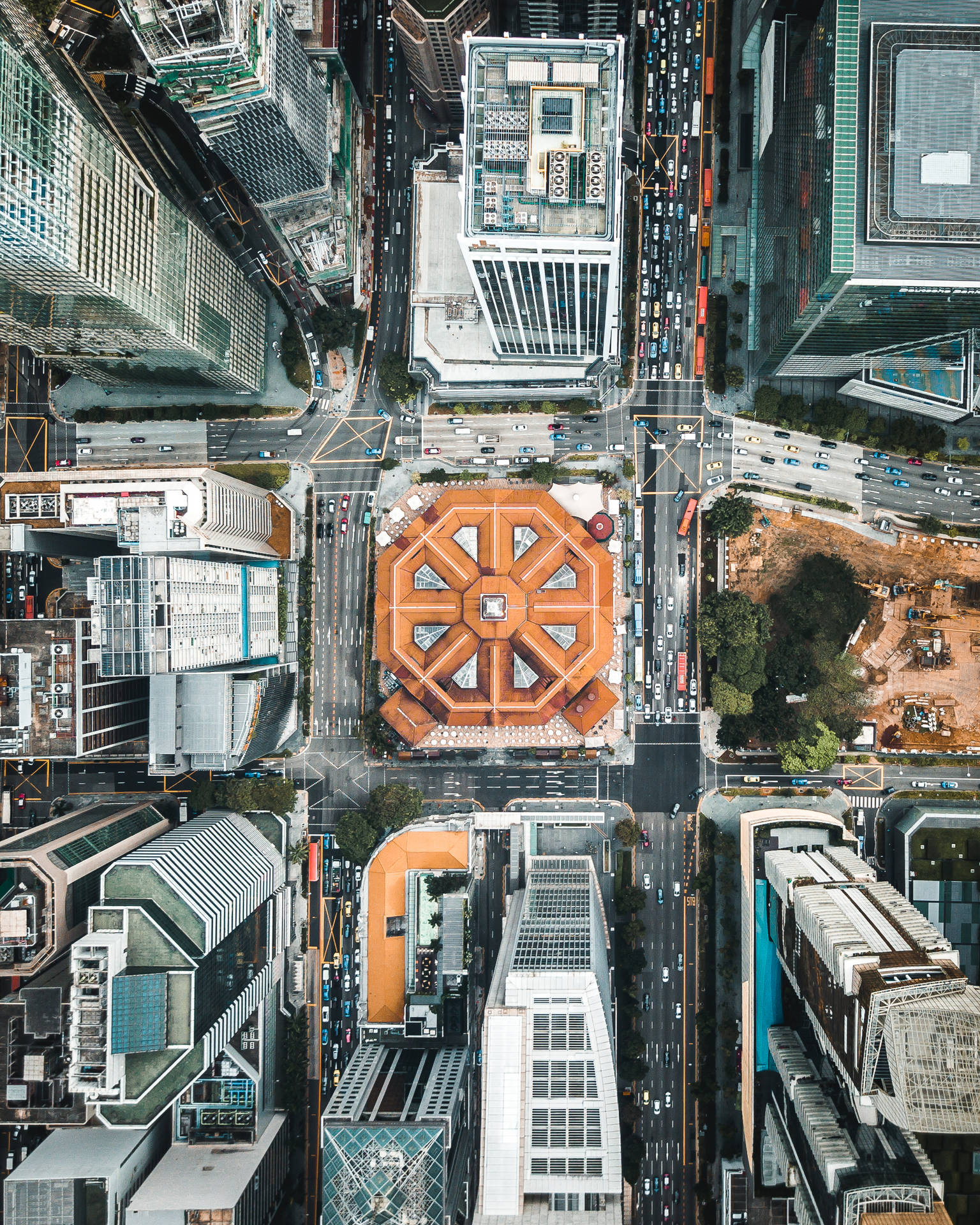 密集城市區域的俯拍鳥瞰圖，中央有一座橙色建築，周圍環繞著摩天大樓和繁忙道路。
