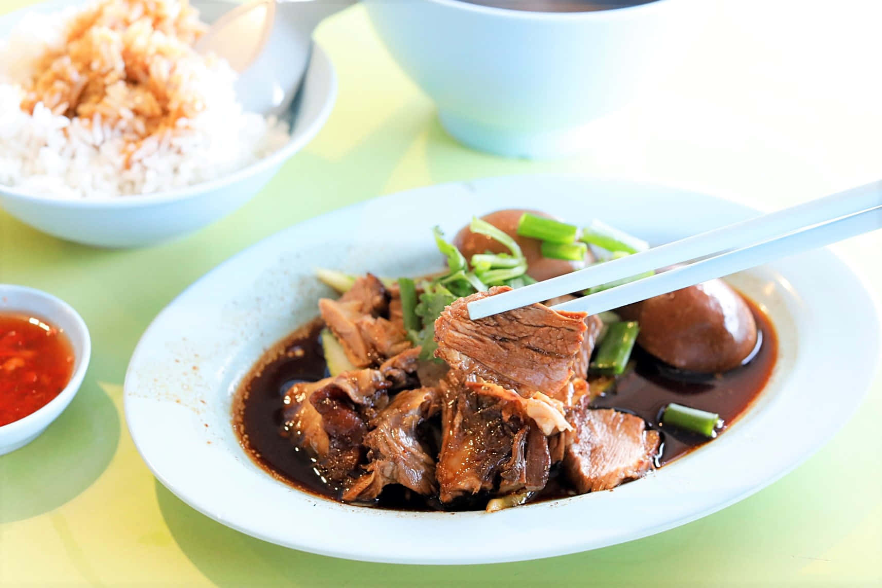 新加坡鴨飯：Tekka Market 的亨記鵝鴨飯 壁紙 — 嫩滑燉牛肉配雞蛋和青蔥，配上濃郁醬汁，與米飯和辣椒醬一起享用的特寫。