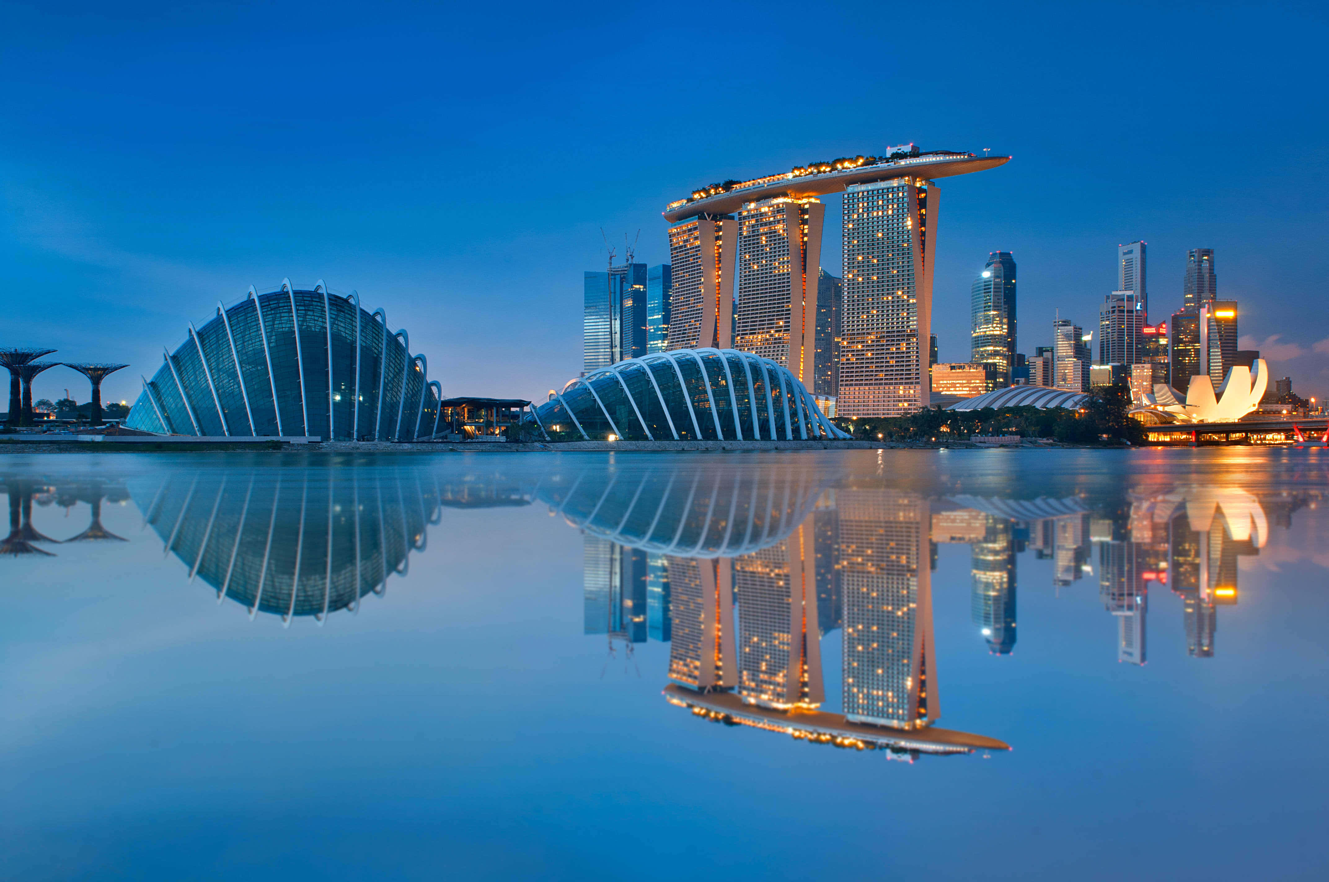 Asia 桌布 壁紙 — 新加坡黃昏天際線，濱海灣金沙和濱海灣花園倒映在深藍色天空下的平靜水面上。