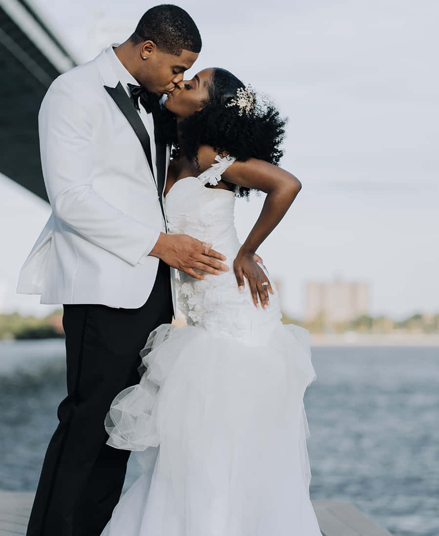 Black And White Wedding 桌布 壁紙 — 新娘和新郎在柔和日光下於海濱碼頭親吻。