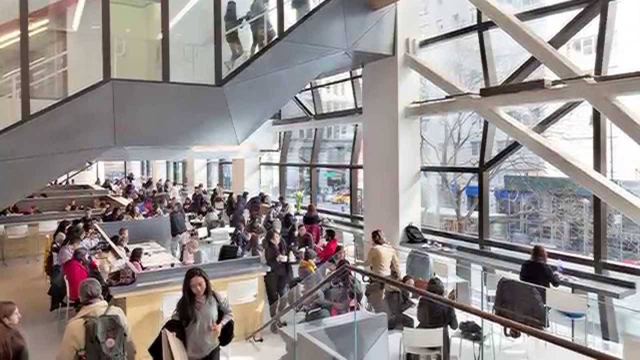 擠滿人的現代圖書館，人們在玻璃中庭學習和走動。