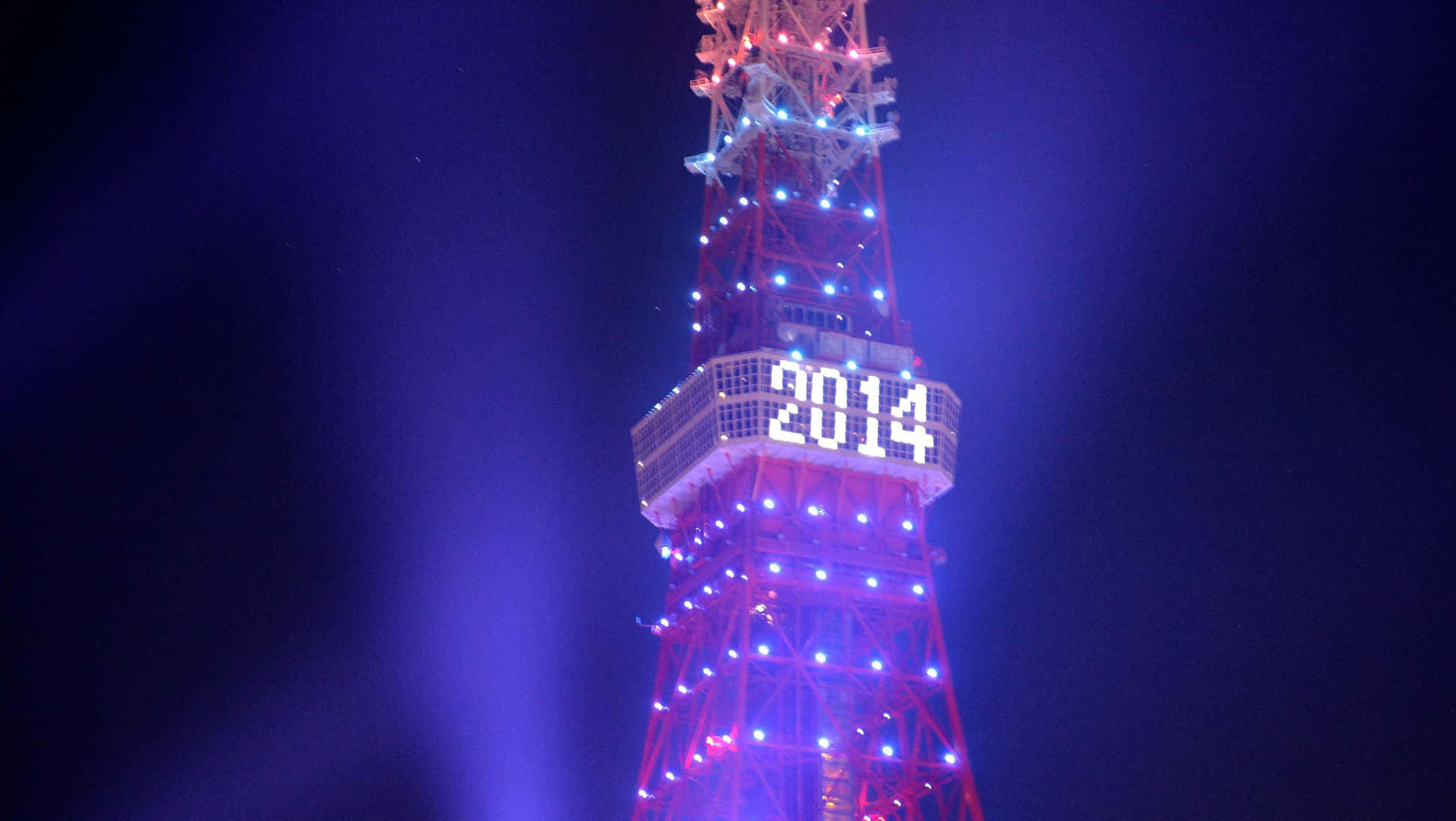 新年夜照亮的黑池塔全景 壁紙 — 東京塔在夜間被發光的藍色和紅色燈光照亮，中間部分有一個明亮的2014數字顯示屏。