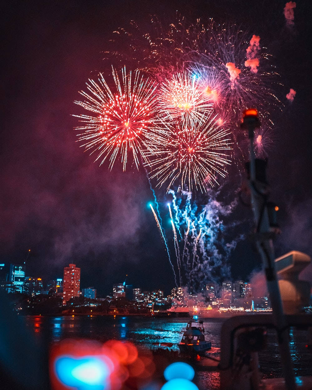 夜間在水面上反射的城市天際線上的彩色煙火。