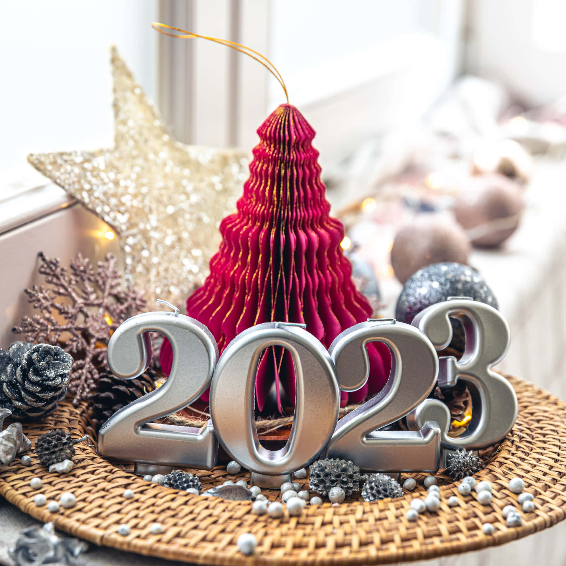 2023年新年節日裝飾，包括紅色聖誕樹裝飾、松果和編織墊上的閃爍星星。