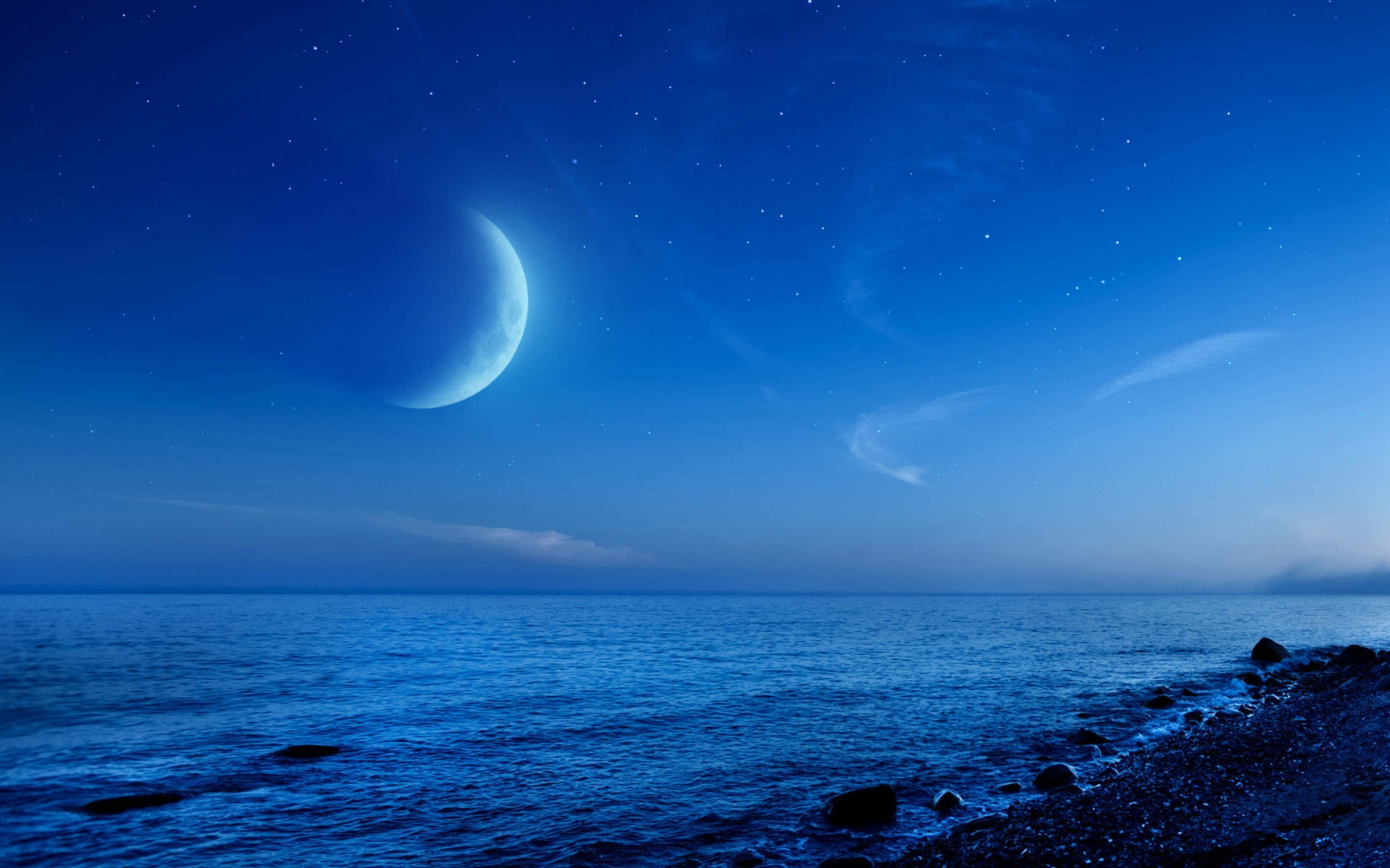 新月夜灘圖 壁紙 — 寧靜的夜晚場景，新月和星星在平靜的藍色海洋與岩石海岸交匯處上方。