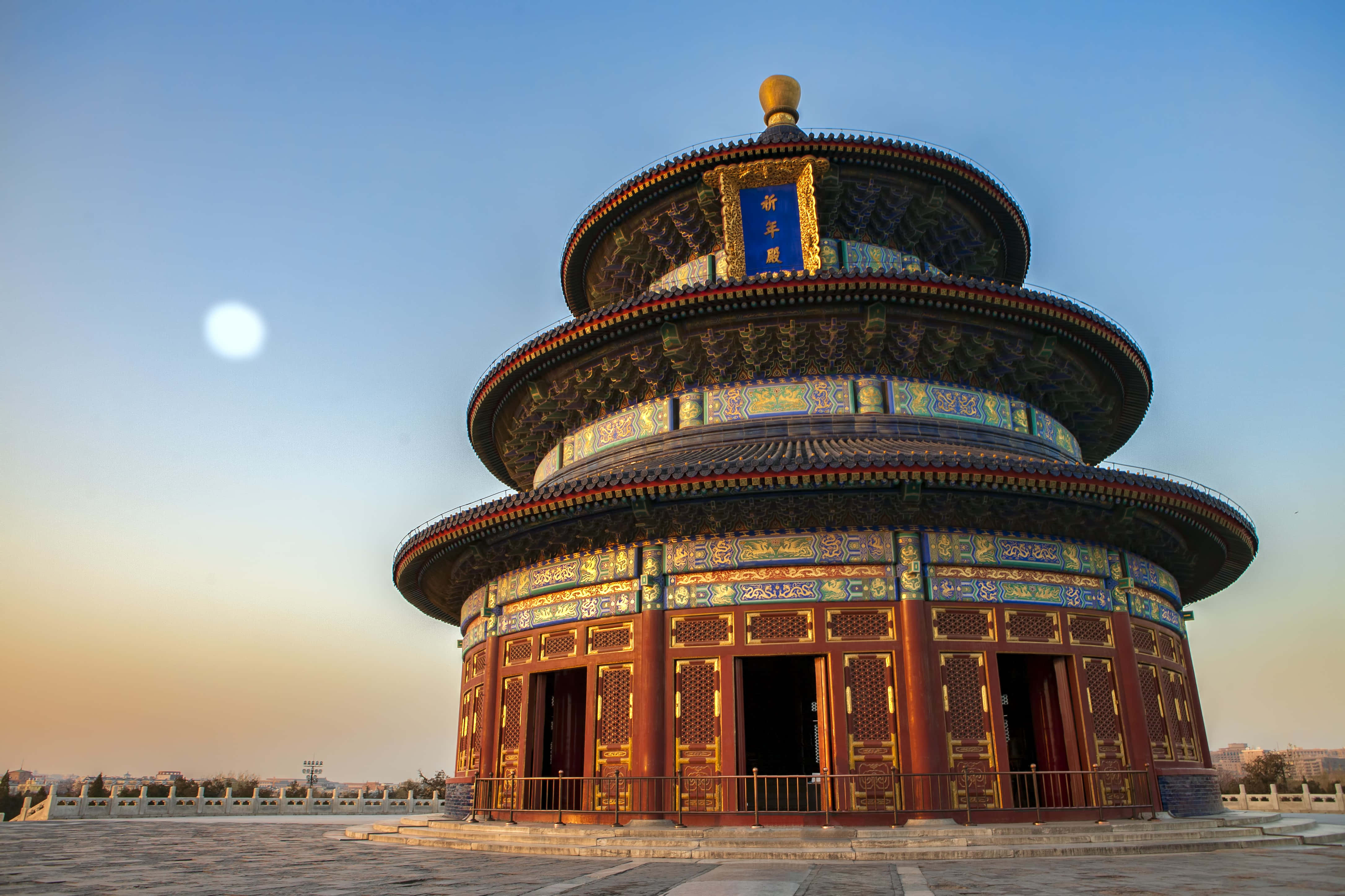 新月高掛天壇上空 壁紙 — 宏偉的圓形寺廟，層疊屋頂綴以金色裝飾，在晴朗天空下沐浴在溫暖的夕陽餘暉中。