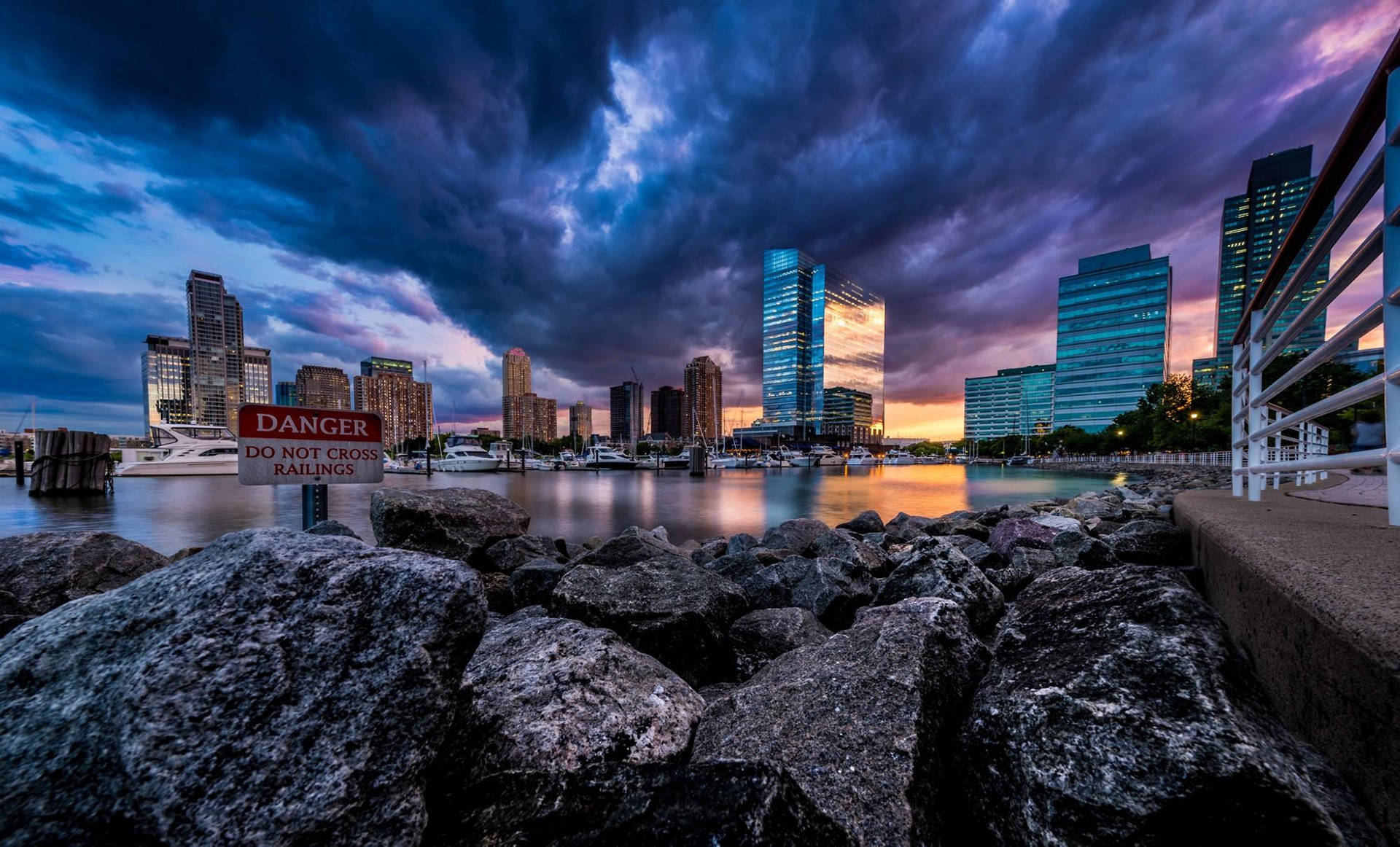 黃昏時分戲劇性的城市天際線，暴風雲覆蓋水面和前景的岩石。
