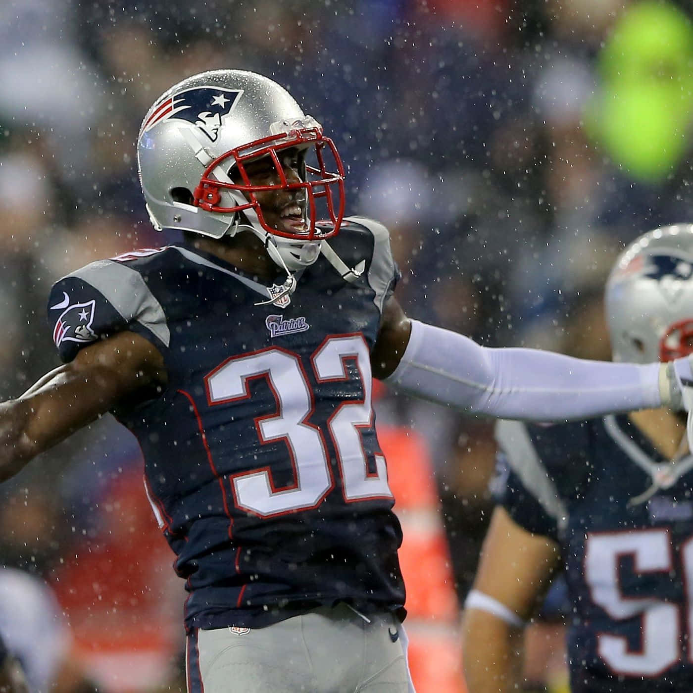 Devin Mccourty 桌布 壁紙 — 新英格蘭愛國者隊32號美式足球員在夜間比賽中於雨中熱情慶祝。
