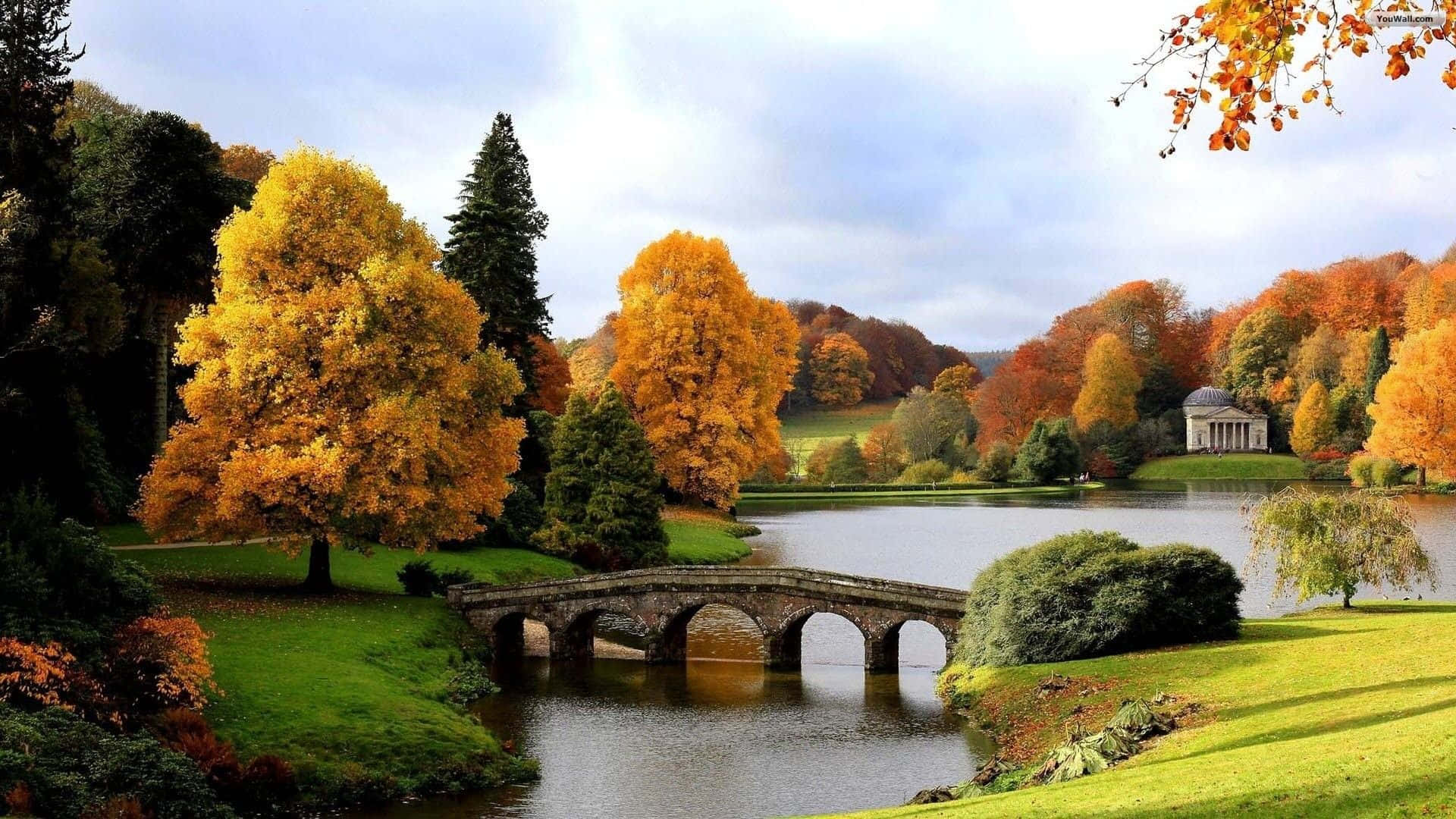 石橋橫跨湖面，背景有秋樹和古典寺廟。