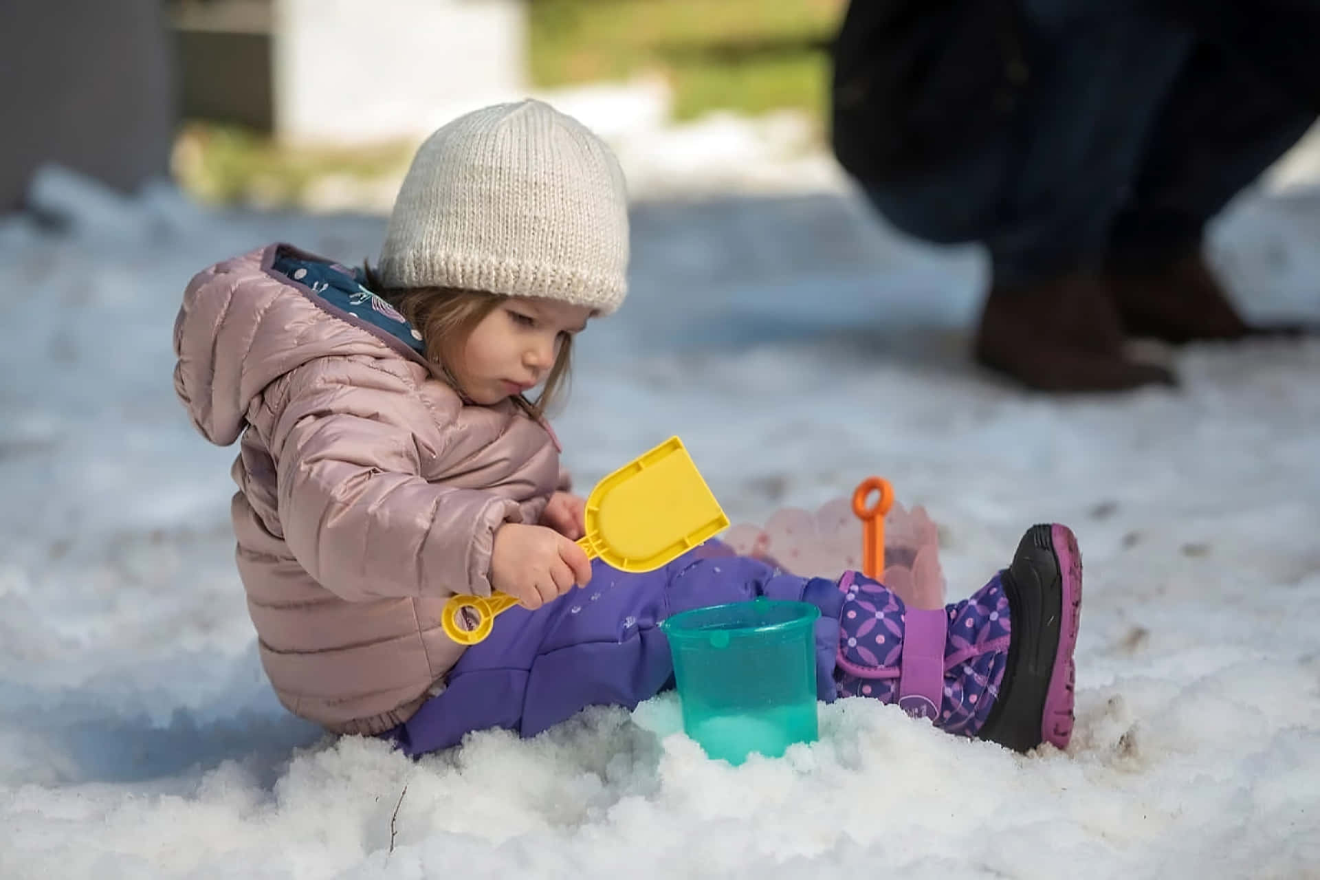 小孩穿著冬裝在雪地裡玩彩色玩具