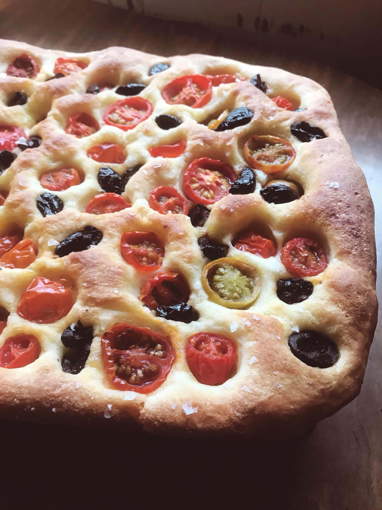 Black Olives 桌布 壁紙 — 新鮮出爐嘅佛卡夏麵包，上面鋪咗半邊車厘茄同飽滿嘅黑橄欖。