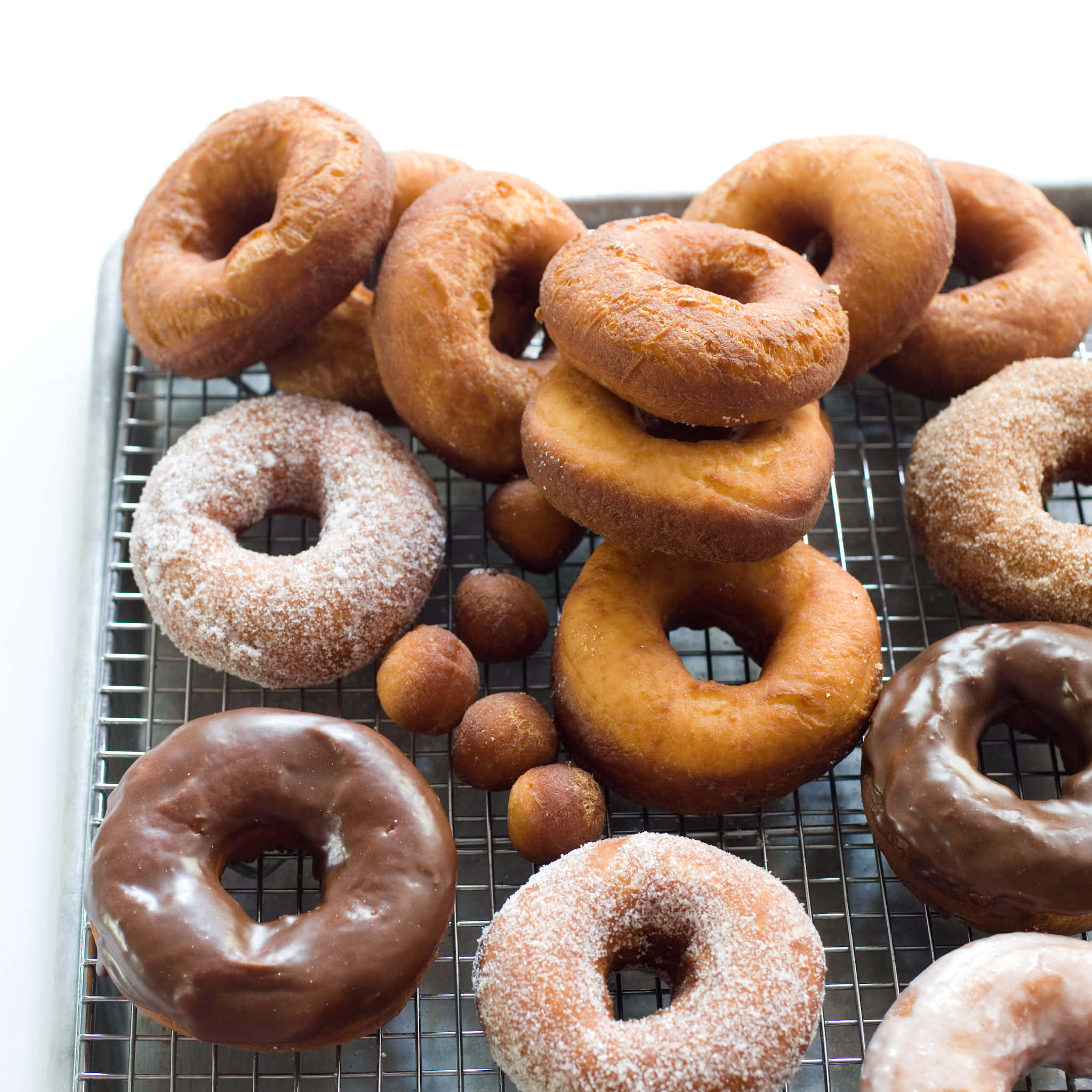 Glazed Donut 桌布 壁紙 — 新鮮出爐的冬甩，配上朱古力糖霜、糖衣和肉桂糖，堆放在冷卻架上。