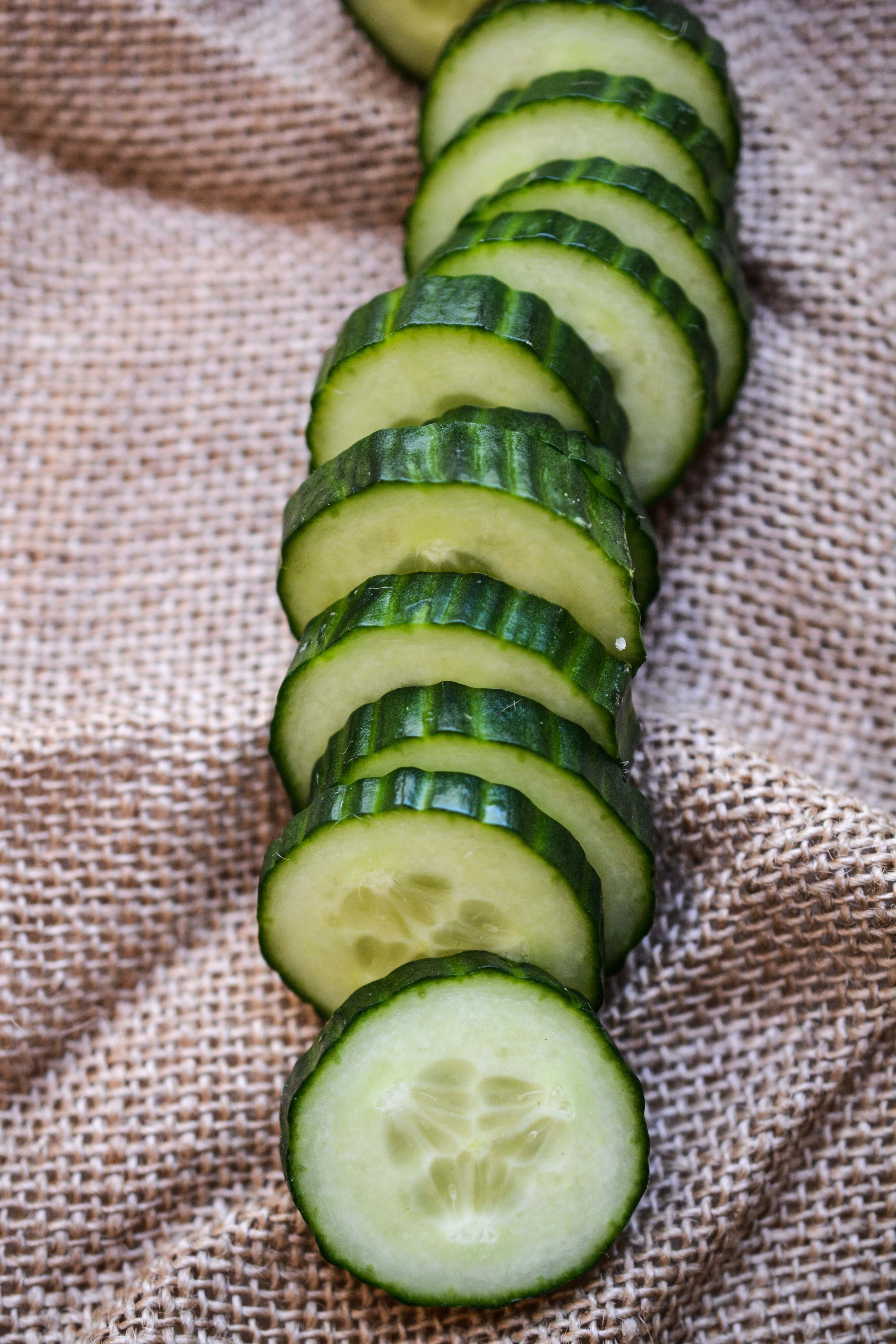 cucumber 桌布 壁紙 — 新鮮切片青瓜以彎曲線條排列在質感米色粗麻布上。