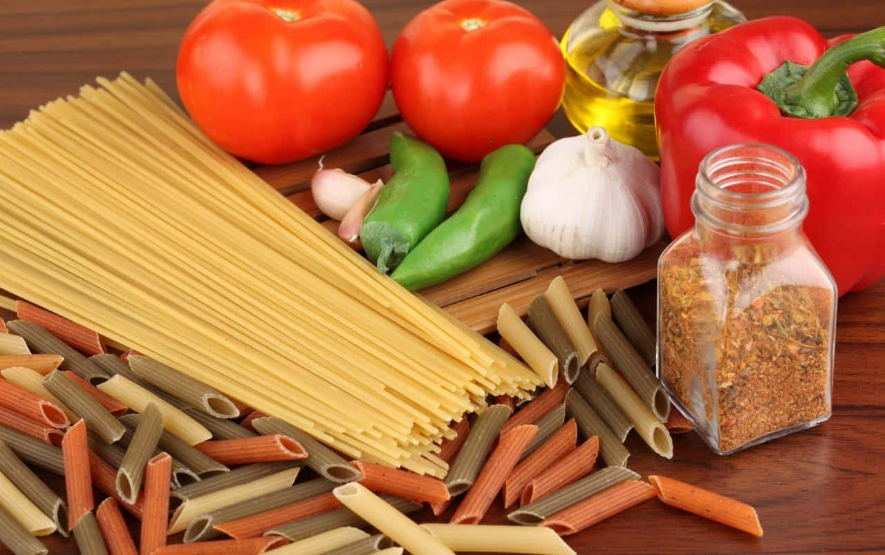 Pasta 桌布 壁紙 — 新鮮意粉食材的鮮豔排列，包括番茄、燈籠椒、大蒜和香料，擺放在木質表面上。