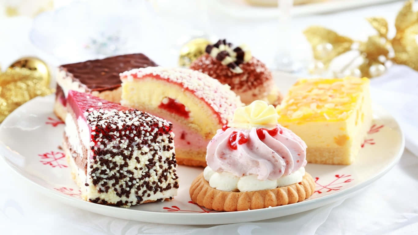 新鮮烘焙糕點 壁紙 — 一盤各式節日甜品，包括朱古力蛋糕、草莓卷和奶油泡芙，飾以金色節日裝飾。