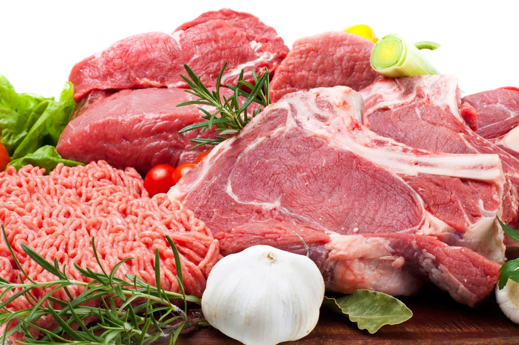Red Meat 桌布 壁紙 — 新鮮生肉，包括牛扒、免治牛肉和大蒜，配以迷迭香和車厘茄，放在木板上。